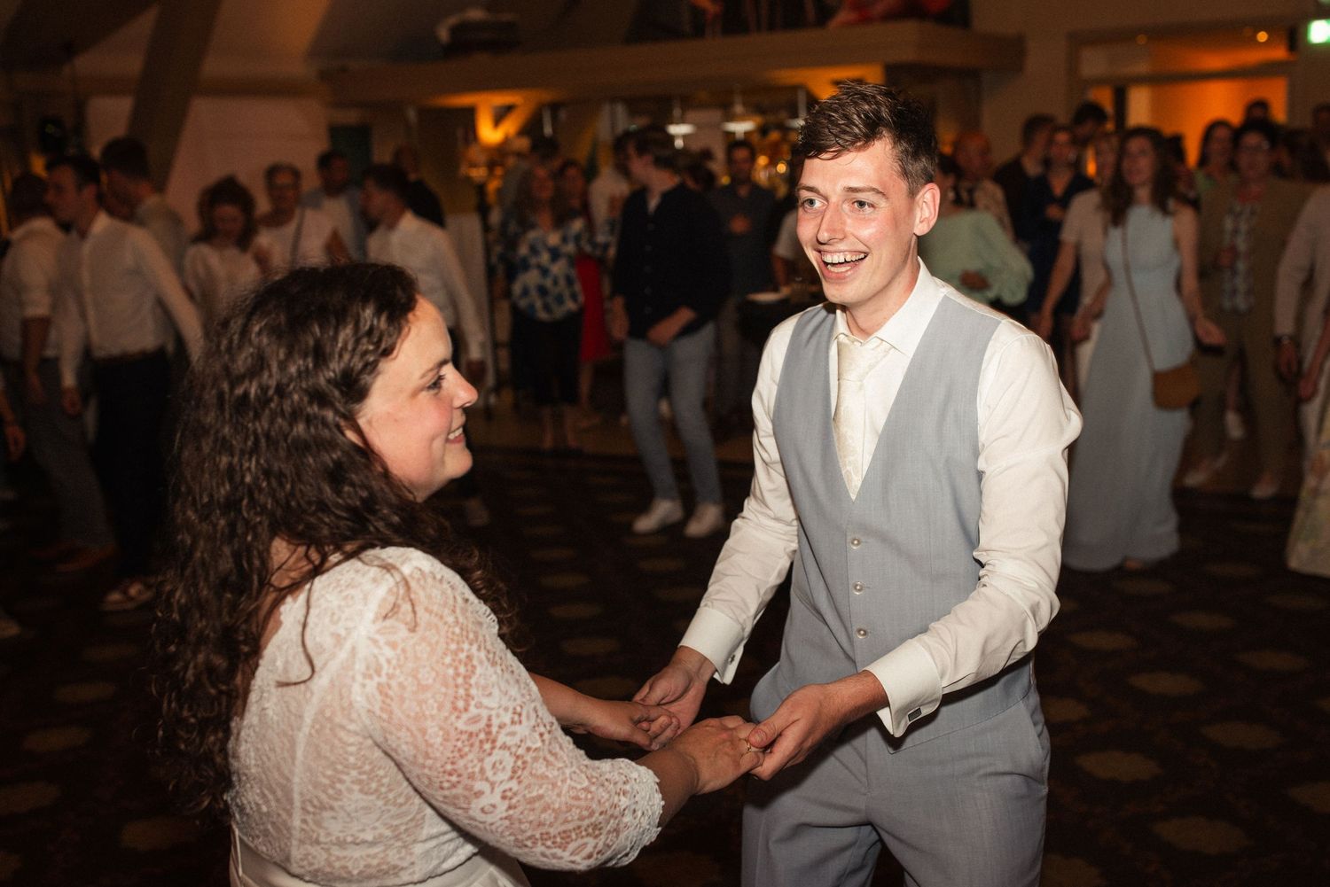 A couple dances together on a lively dance floor at a wedding reception.