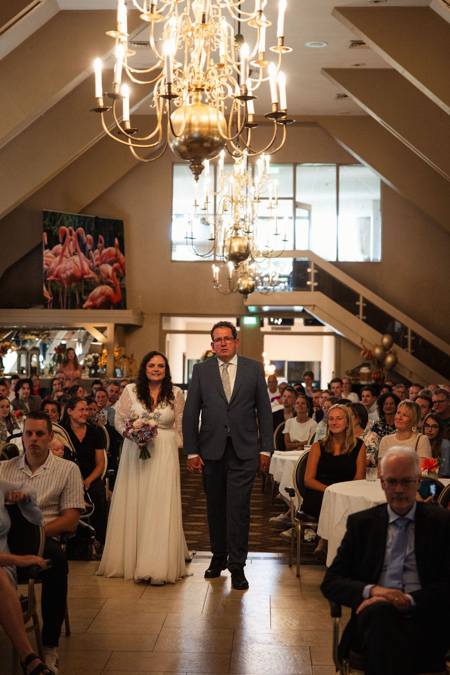 Elegant wedding ceremony in a venue with chandelier lighting and guests in attendance.