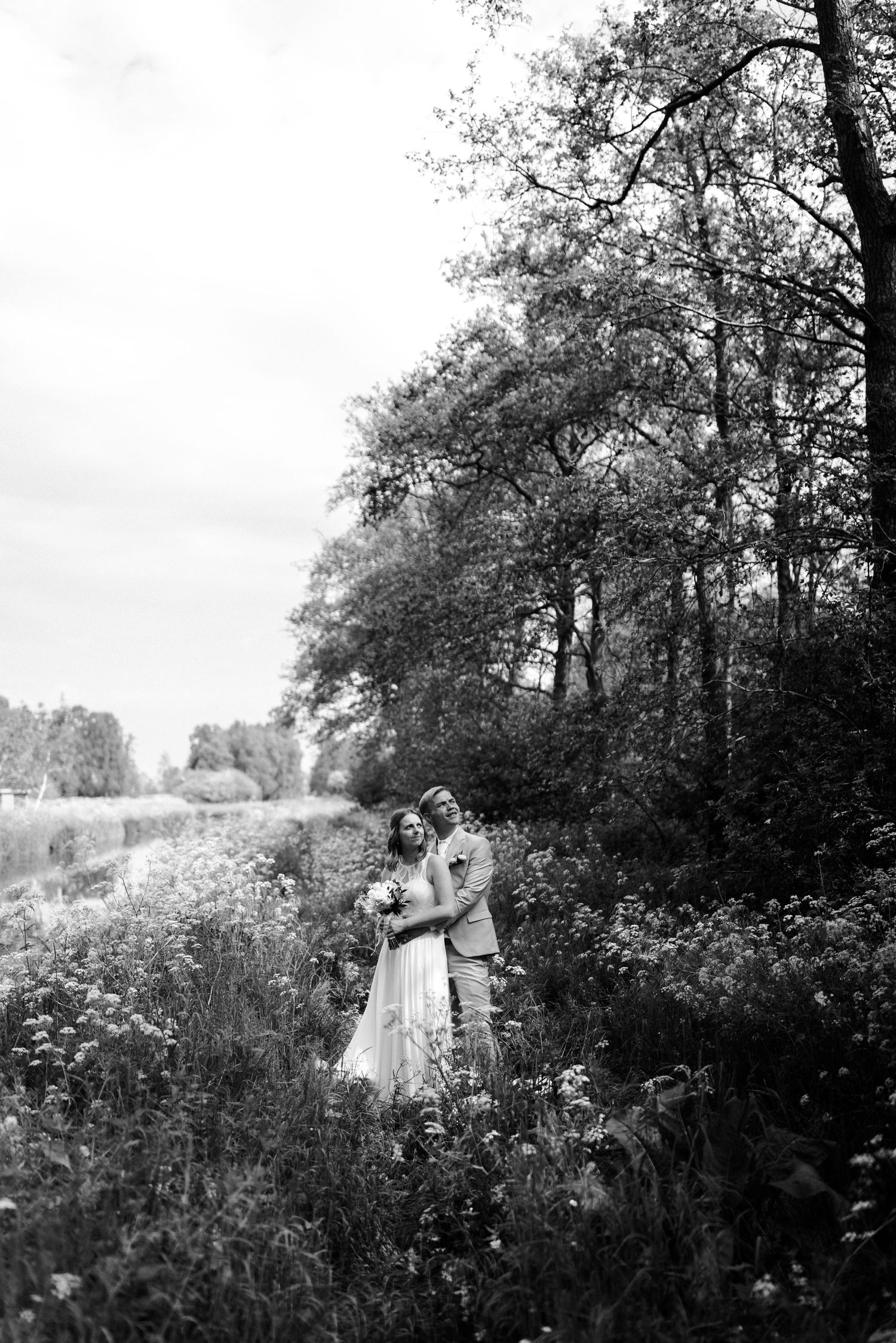 Black and white portrait of a couple embracing in a wildflower meadow.