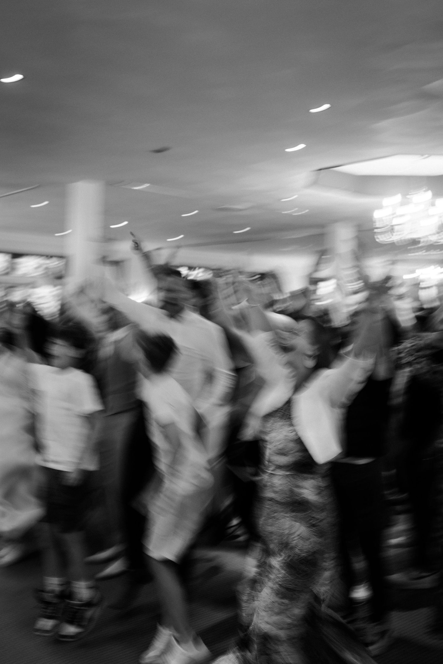 Blurred black and white motion shot of wedding reception dance floor with crowd.