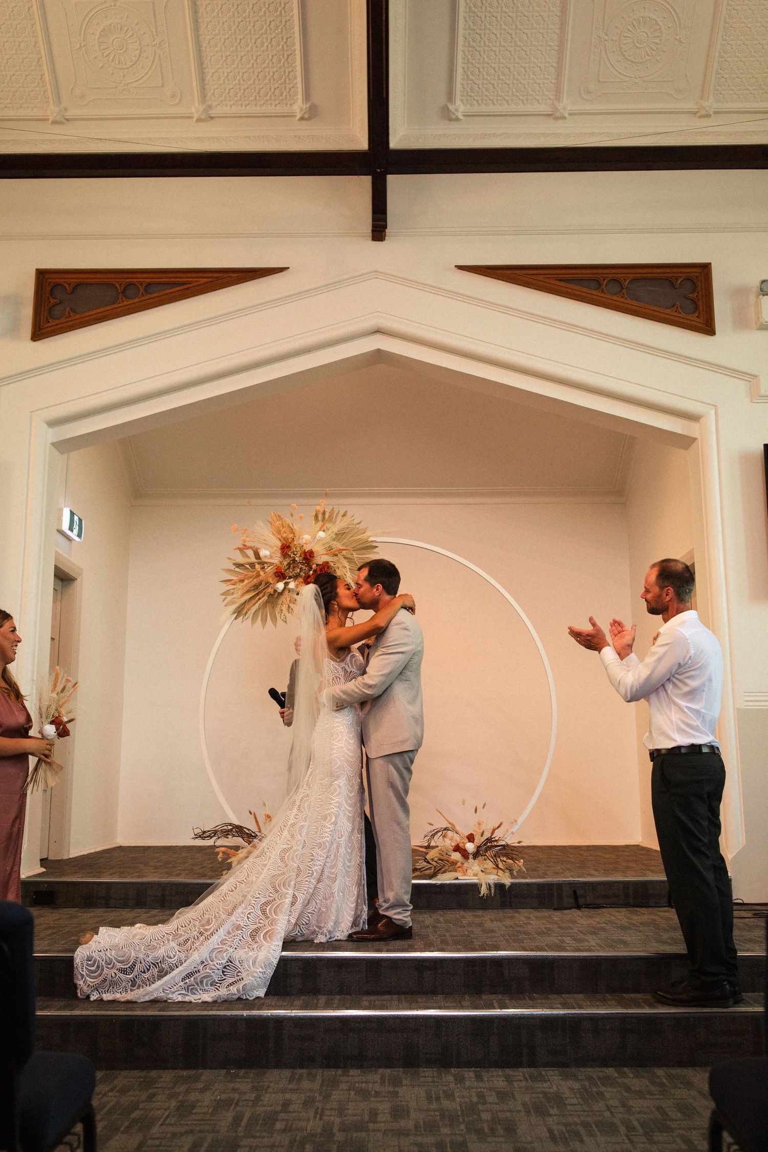 Wedding ceremony under an arched altar with dried palm decorations in a church setting.