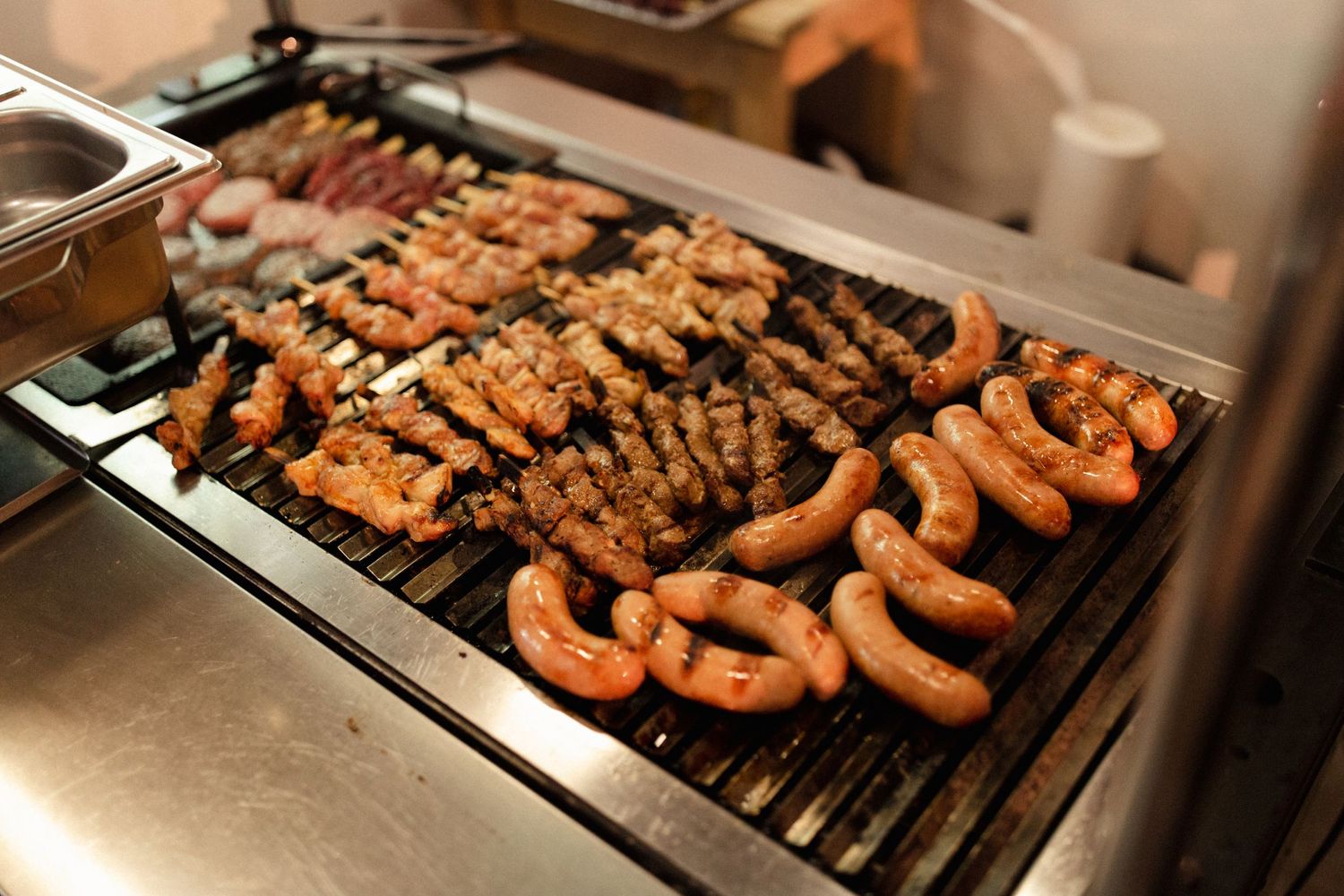 Grilled sausages and meat on a large commercial grill with grill marks visible.