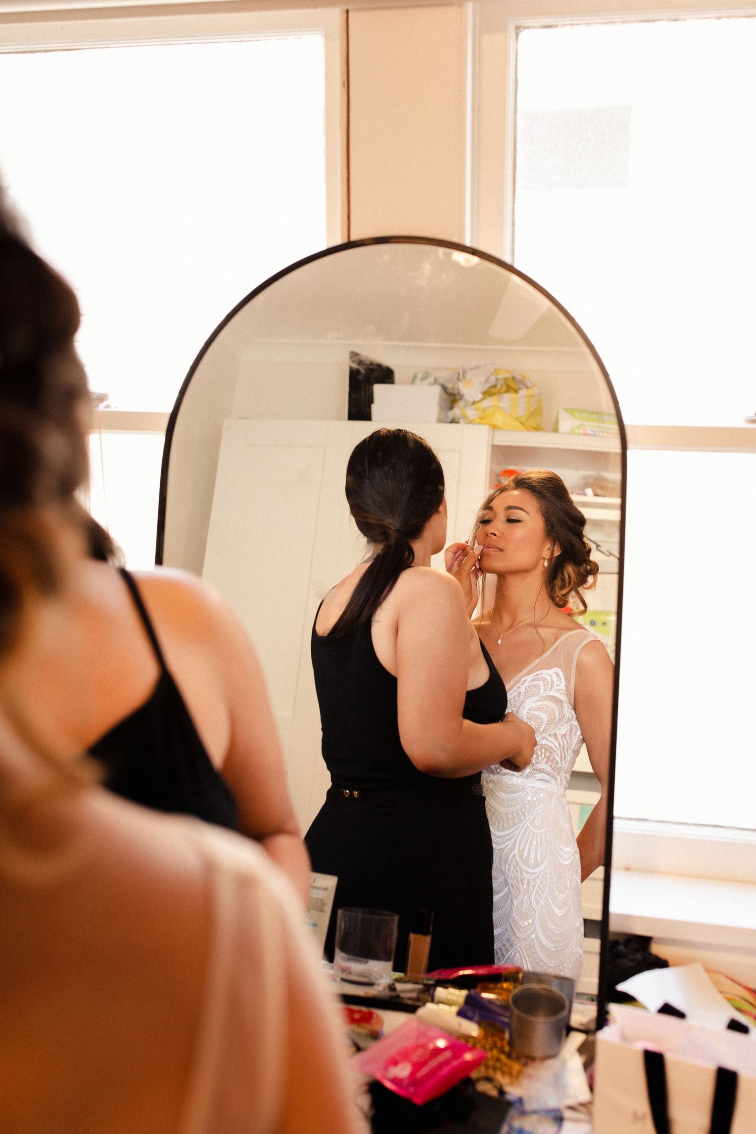 A pre-wedding preparation scene reflected in a mirror with makeup and styling in progress.