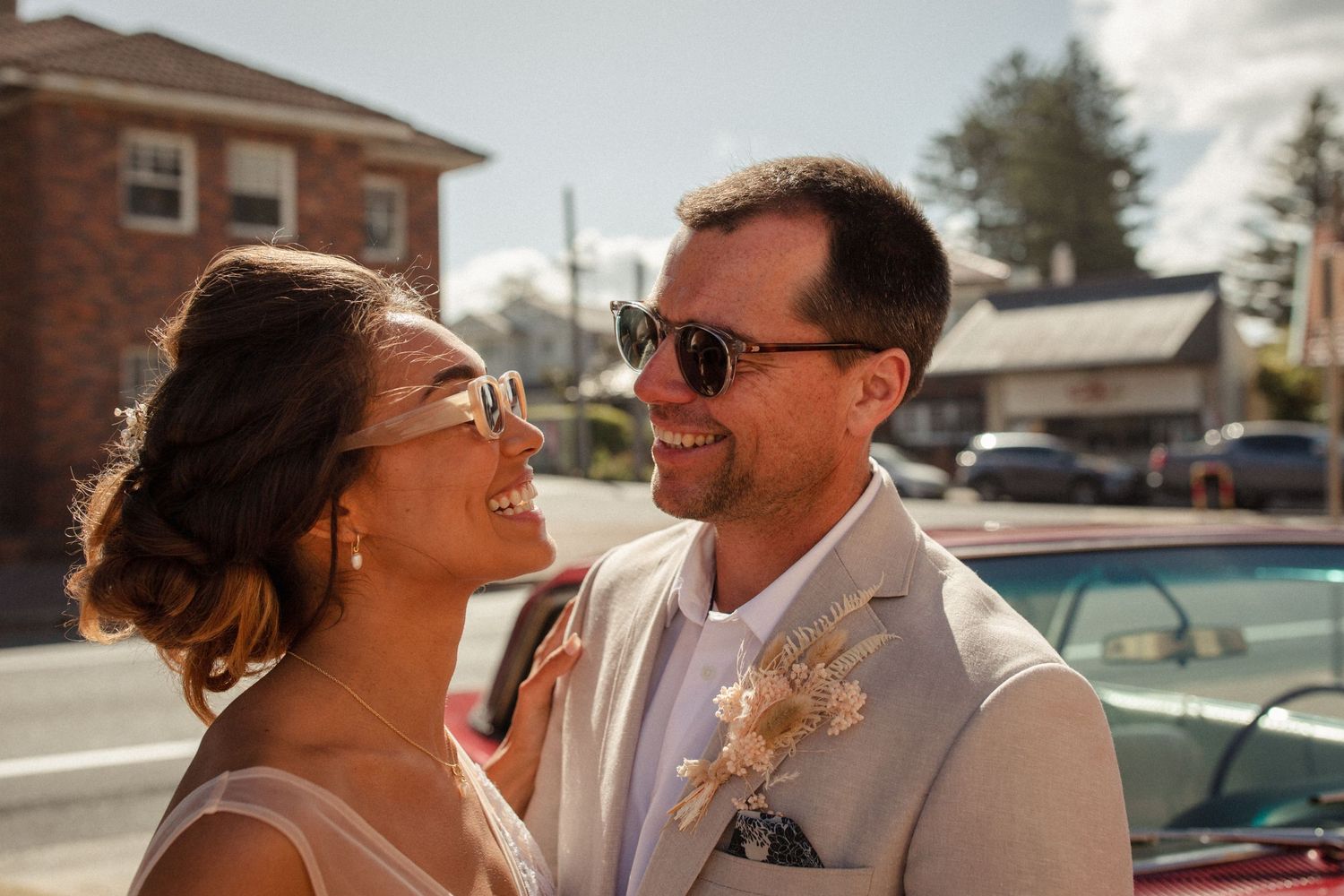 A joyful candid moment between newlyweds outdoors with vintage buildings in background.