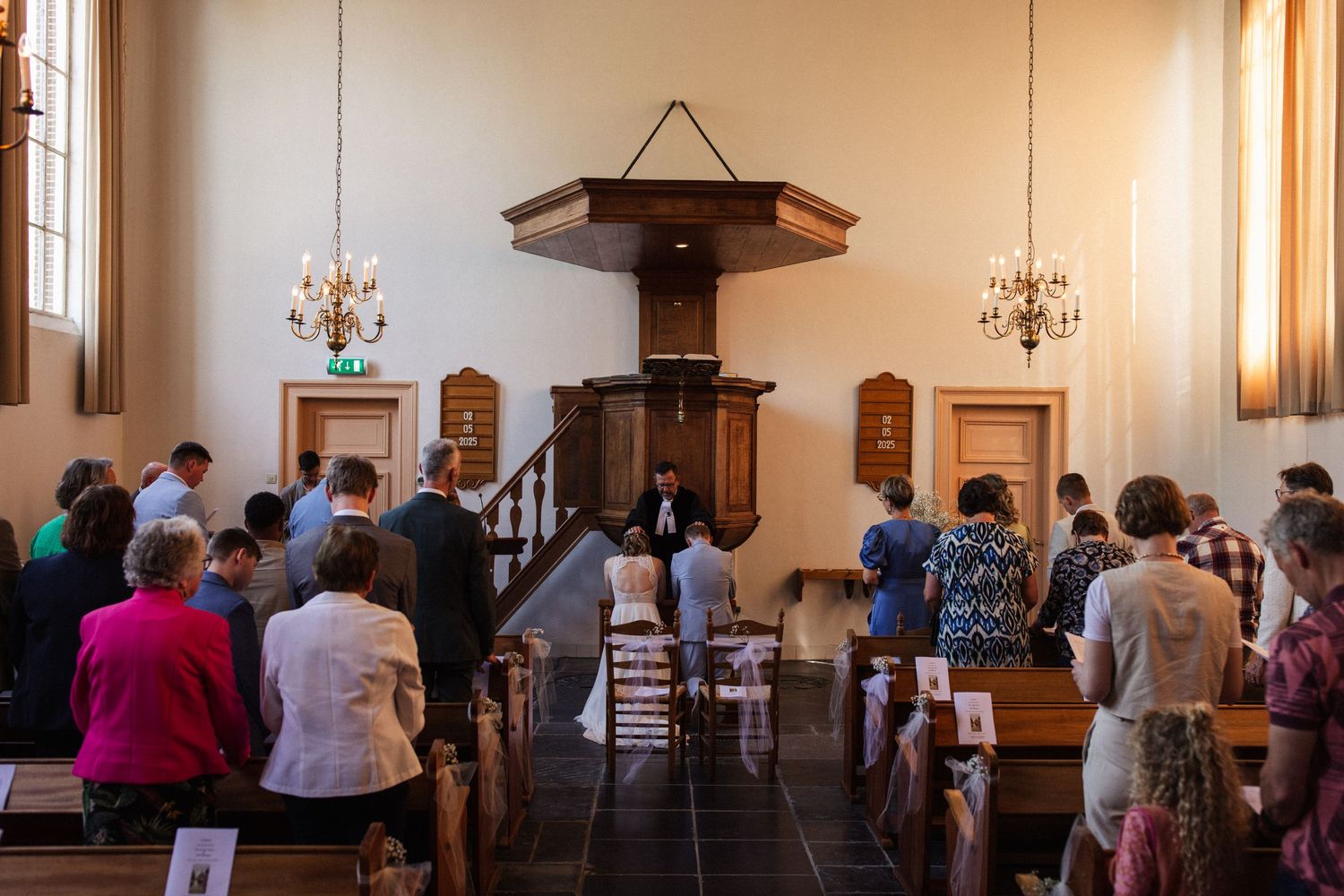 Guests gather in a traditional church sanctuary with wooden pews and a raised pulpit for a wedding ceremony.
