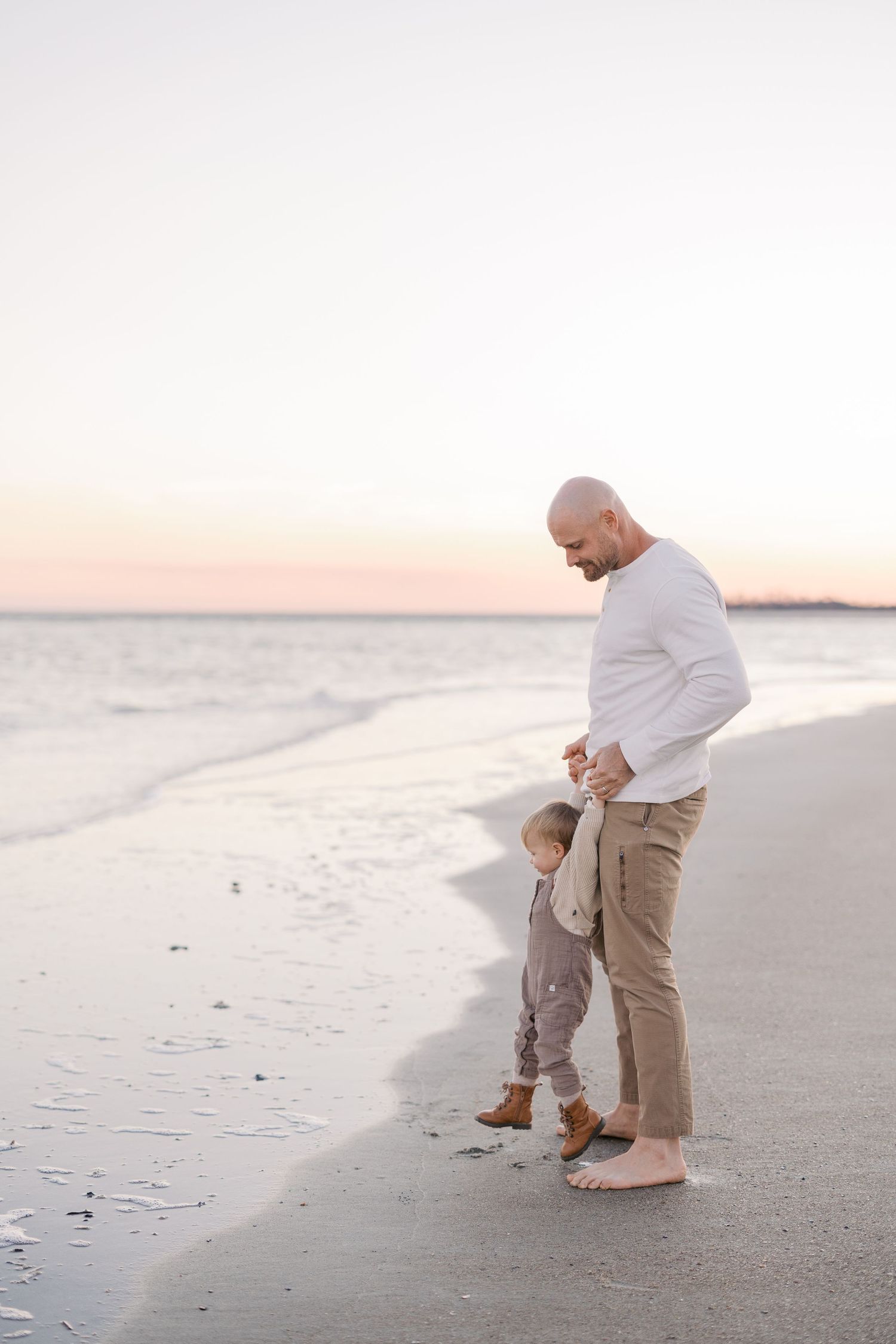 Parent and child sharing tender moments while walking along a peaceful beach at sunset.