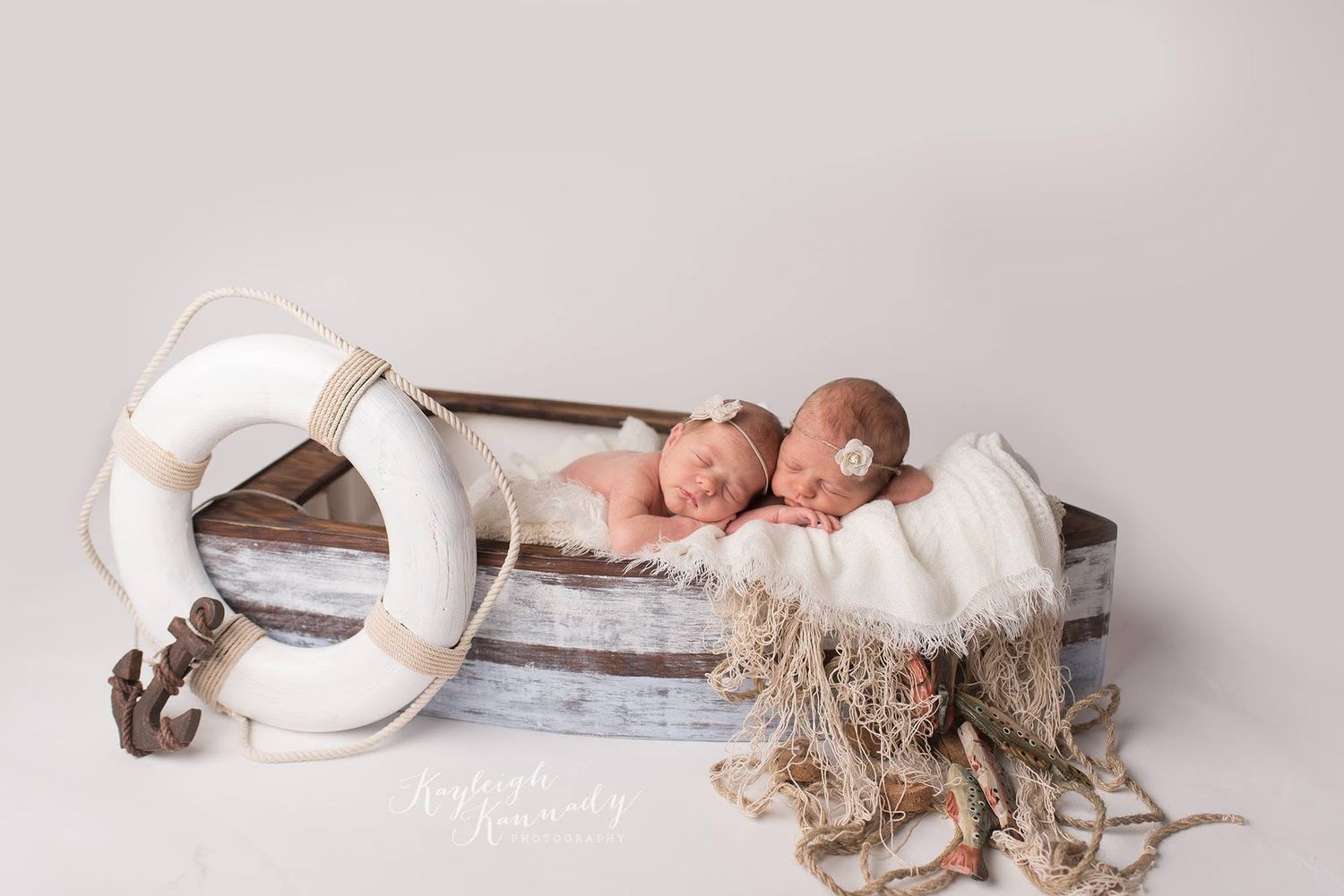 twin newborn girls in a small sail boat posed for newborn poictures