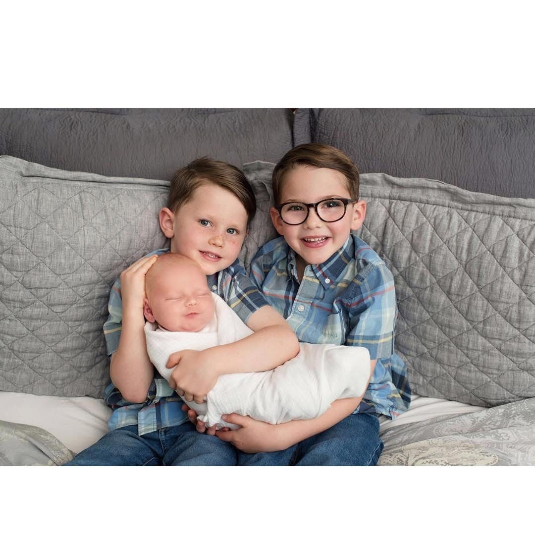 3 brothers together snuggling their  newborn brother