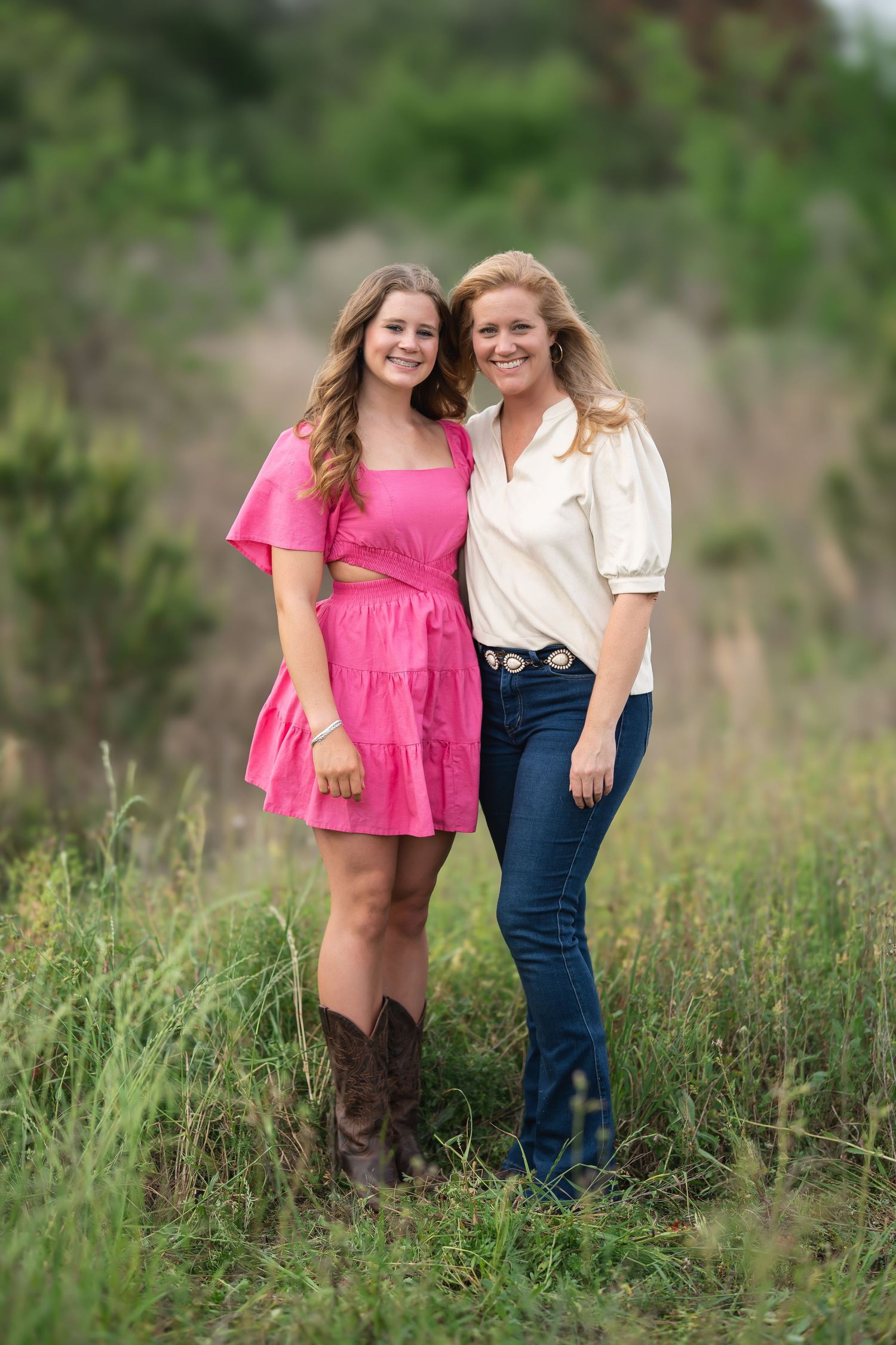 beautiful mother-daughter duo in smiling in a grassy field