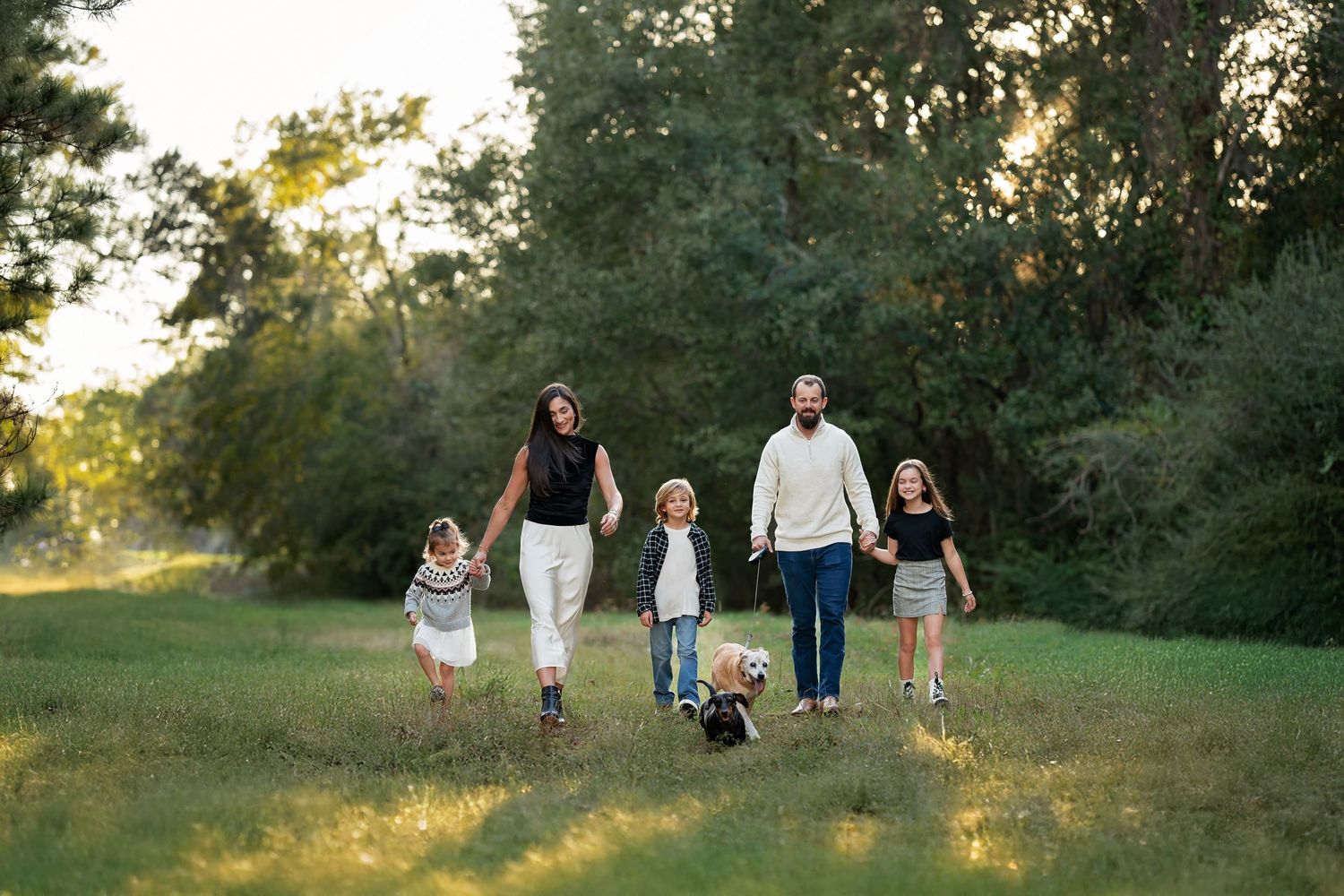 Parents walking hand in hand with kids at sunset during family photo session