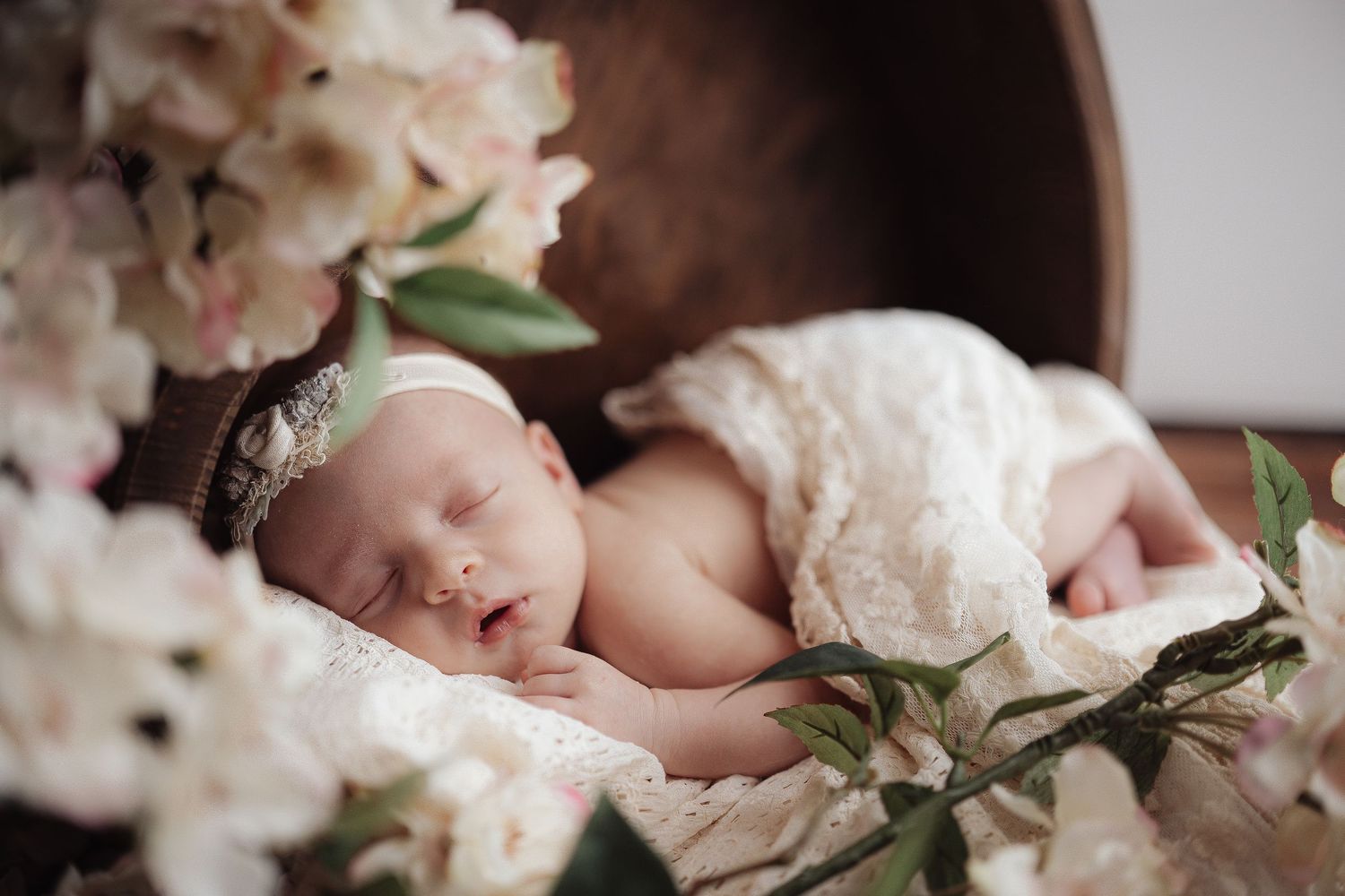 Delicate cherry blossoms frame a peaceful newborn photography session against a soft white backdrop.