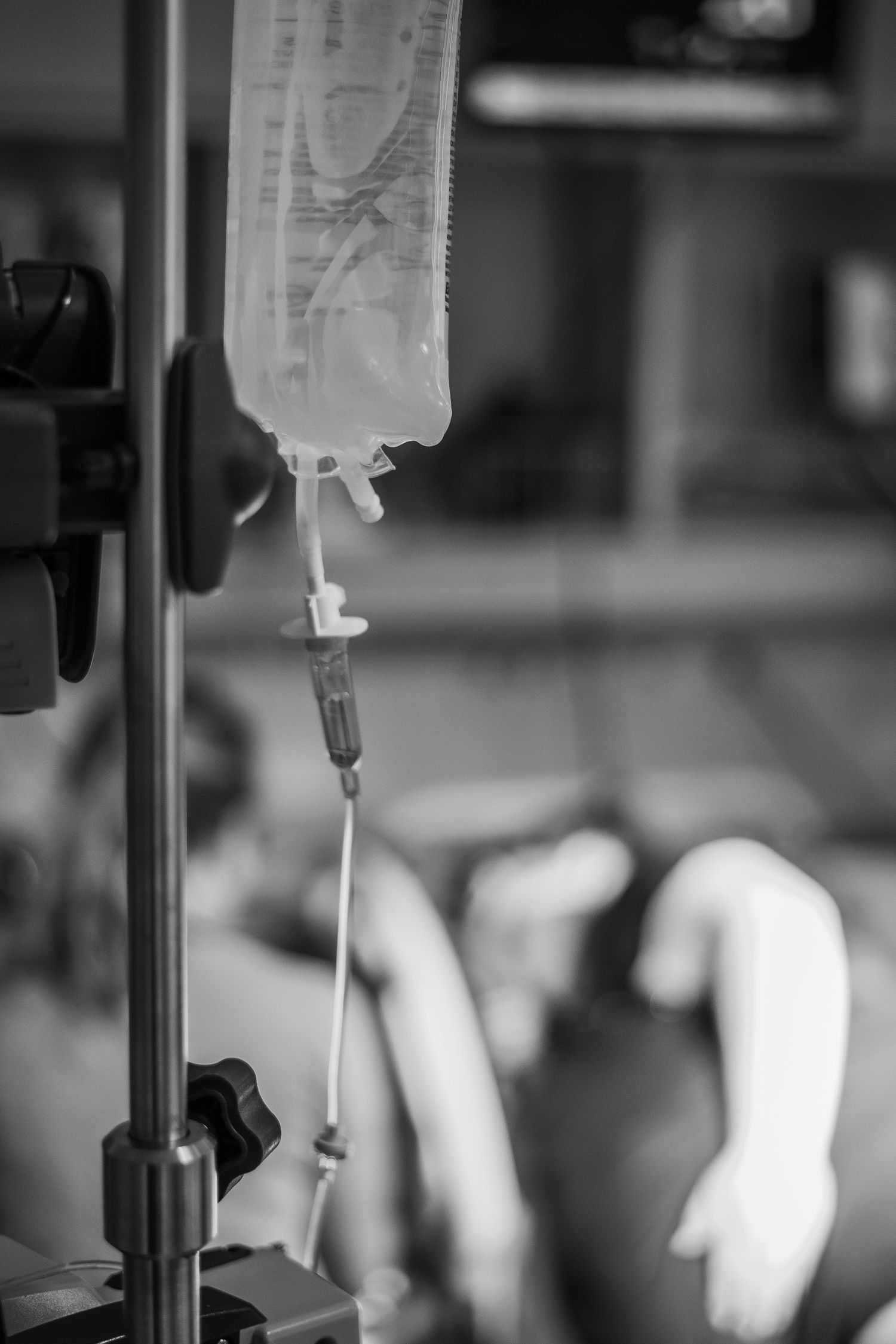Medical IV drip bag and tubing in a hospital setting shown in black and white. Birth Photographer Ontario