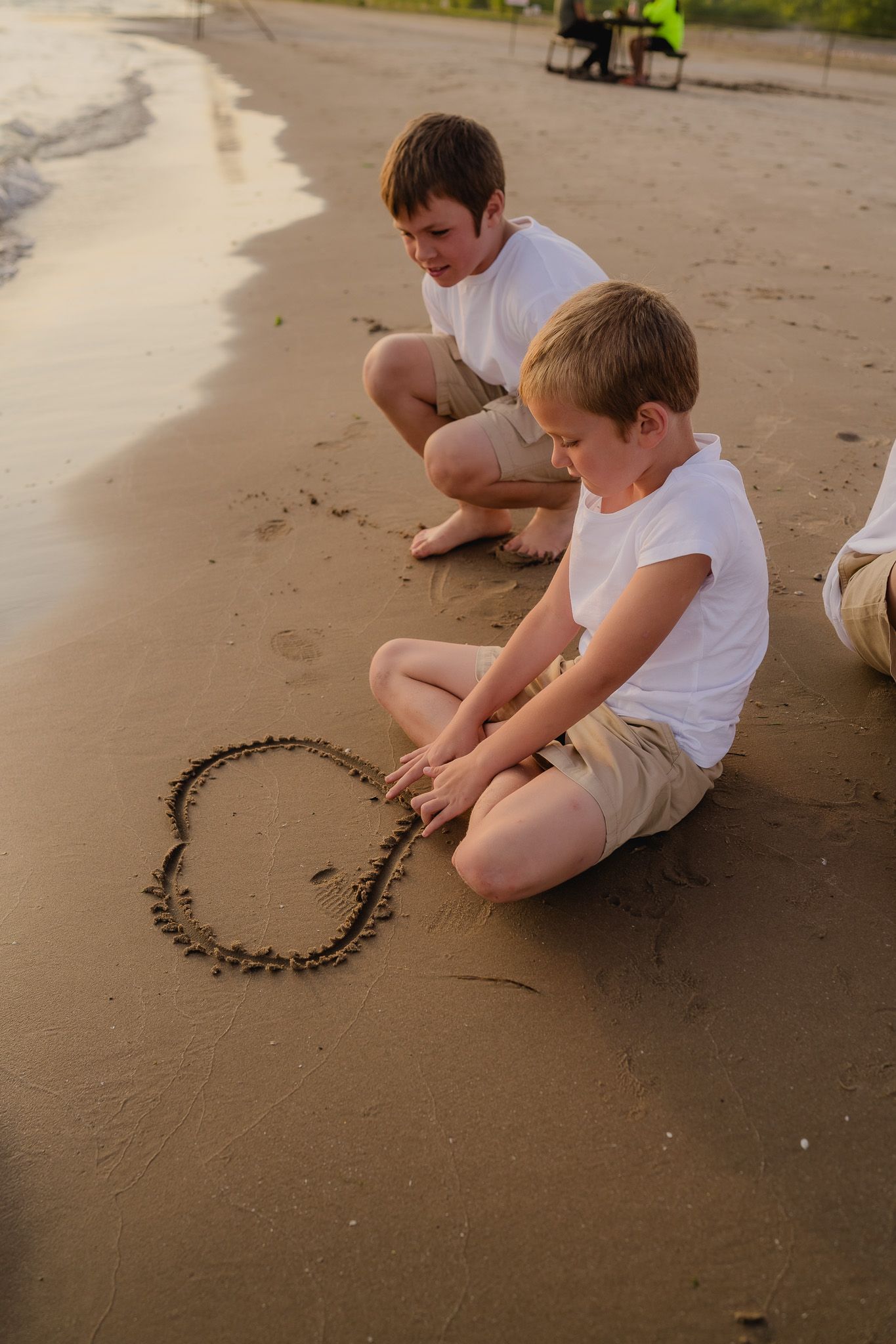 A sequence of photos showing someone drawing a circle in wet sand on a beach.