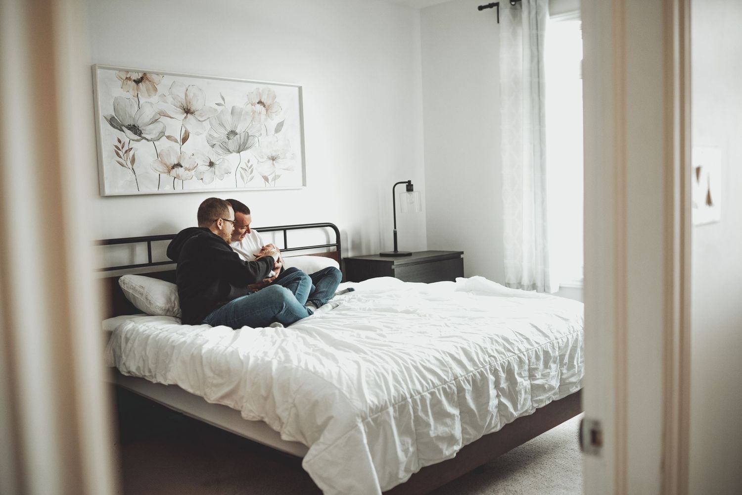 Lifestyle family photography in bright modern bedroom with white decor.