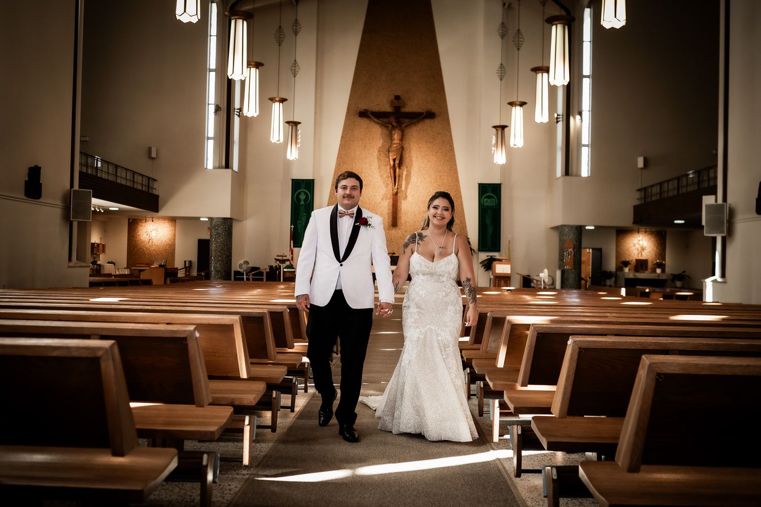 A couple stands together in a beautifully lit church sanctuary during their wedding ceremony.