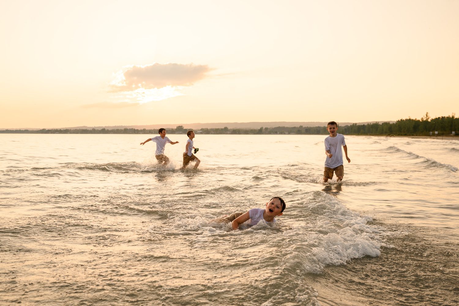 People playing and splashing in shallow ocean water at sunset creating a joyful beach scene.