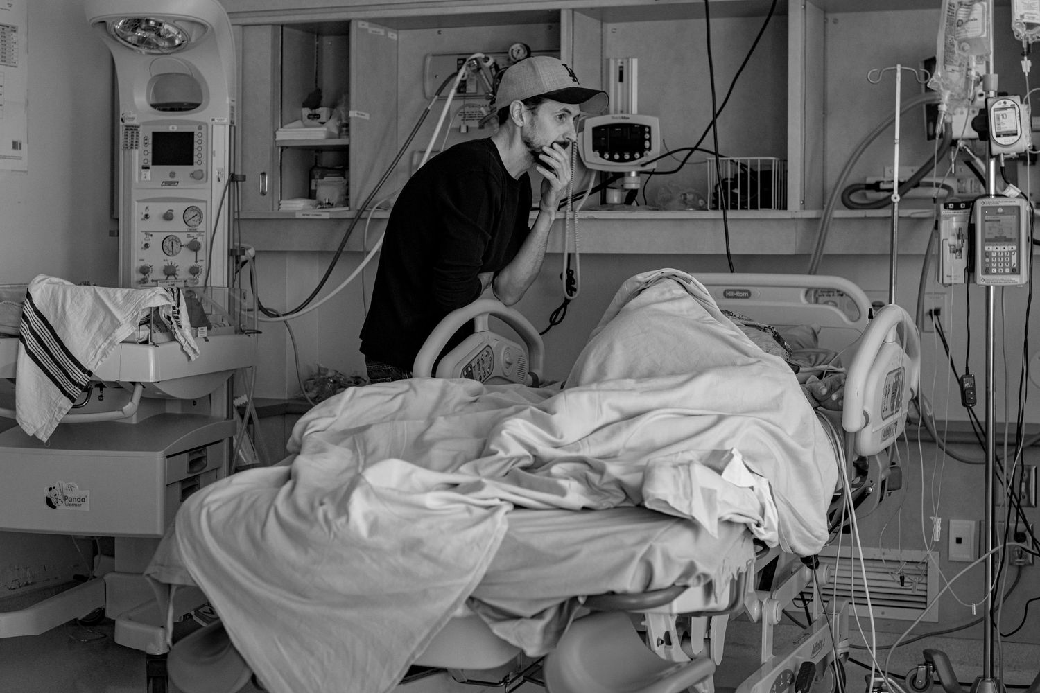 Medical staff attend to a patient in a hospital room with various medical equipment and monitors visible.