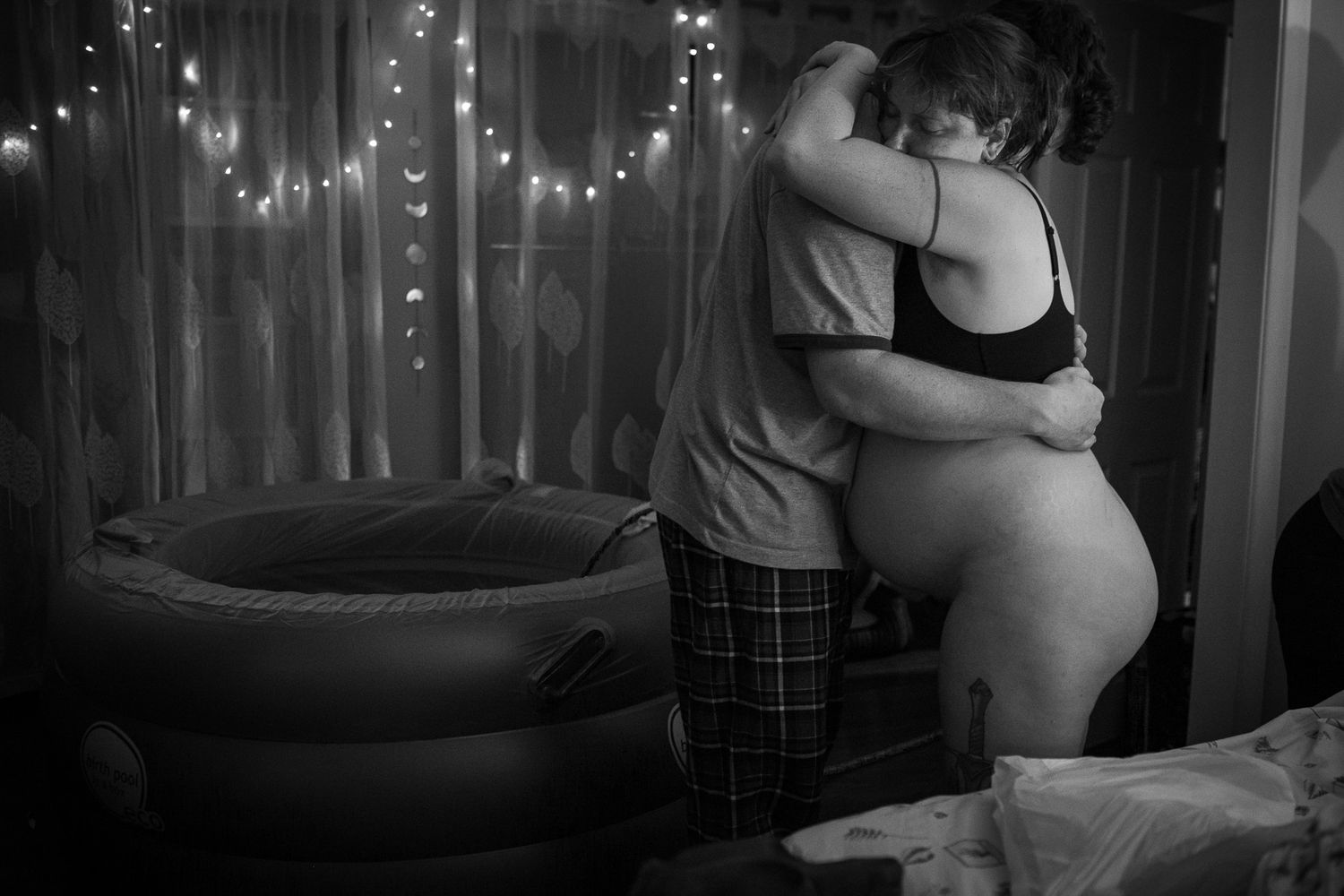A couple dancing intimately in a dimly lit room with string lights creating a romantic atmosphere.