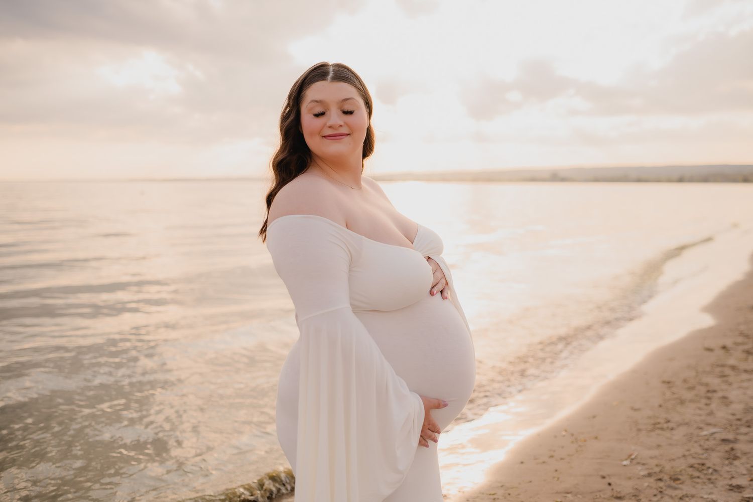 Maternity beach photography session during golden hour with waves and sand. Maternity photographer Ontario