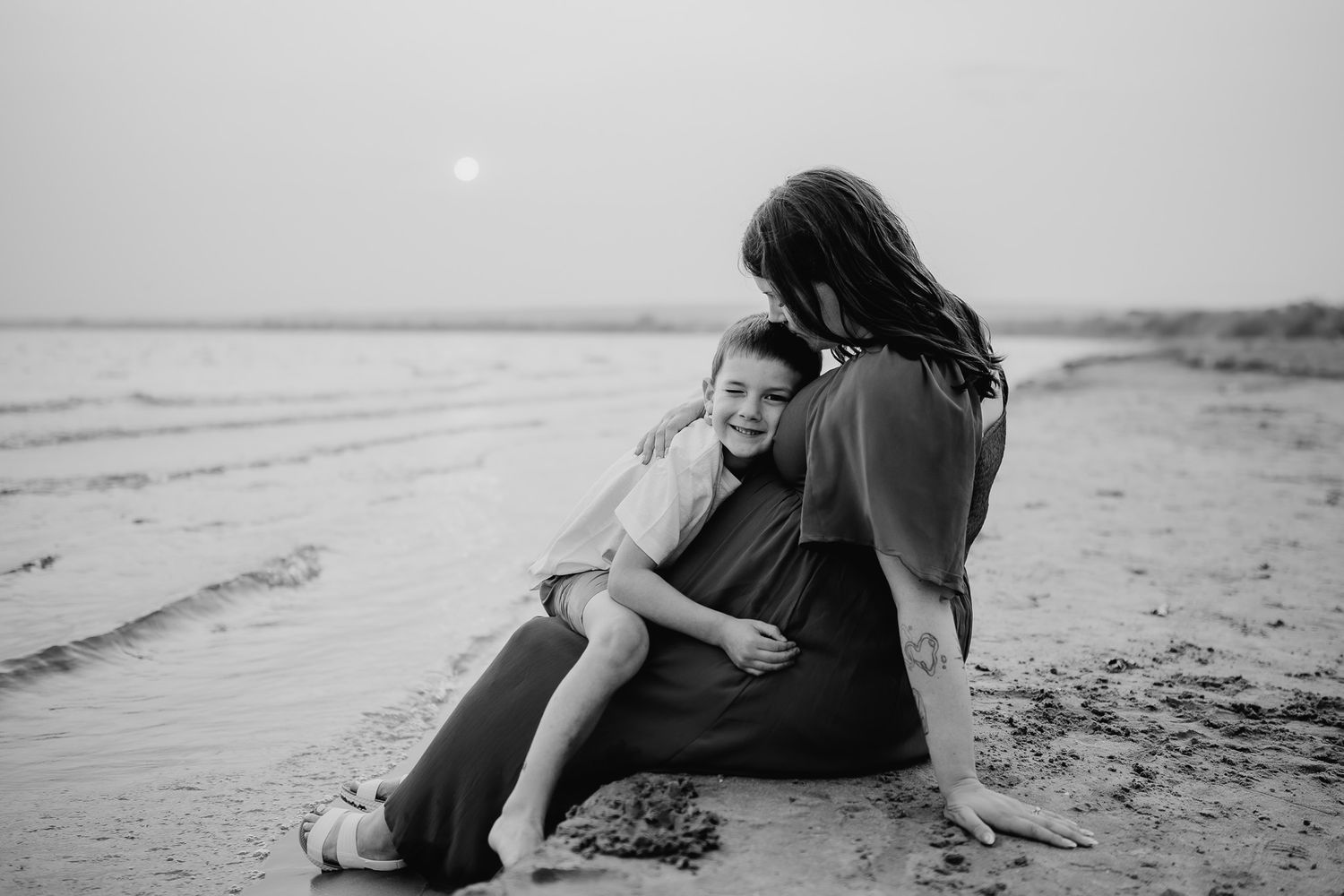 Black and white beach maternity photography session with mother and child on the sand. Maternity photographer Ontario