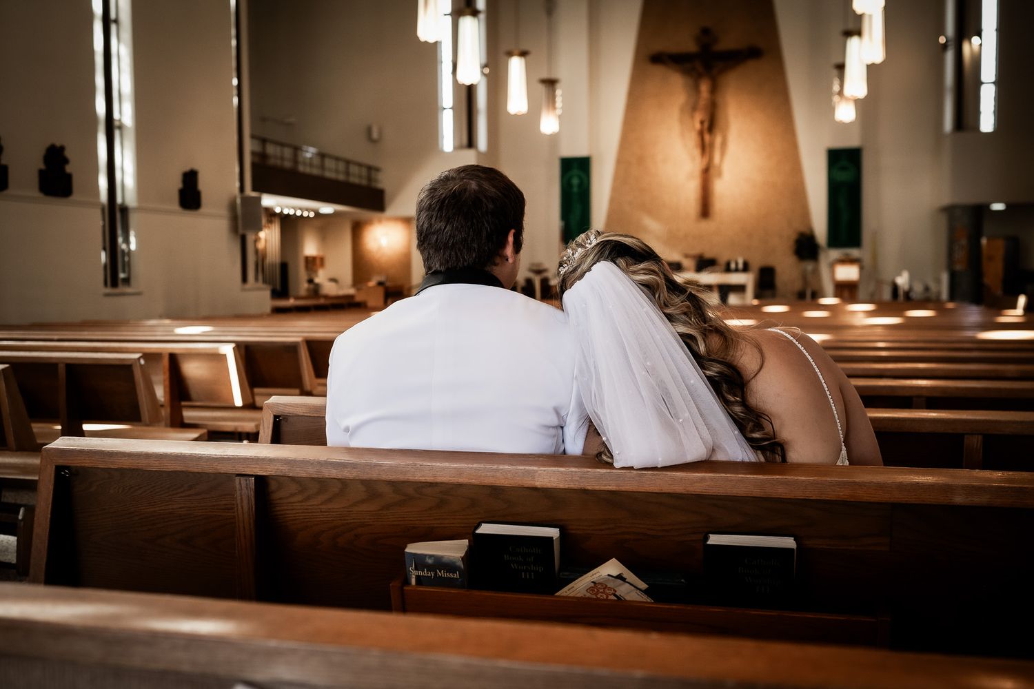 Interior of church with wooden pews and hanging pendant lights creating warm ambiance.
