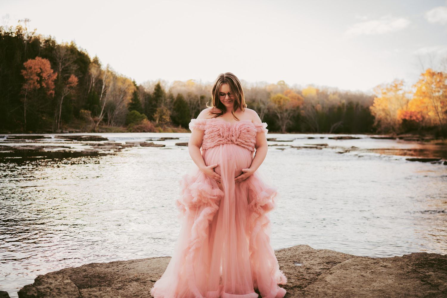 A series of sunset photos at a lake featuring a flowing pink tulle dress against the golden autumn scenery. Maternity photographer Ontario