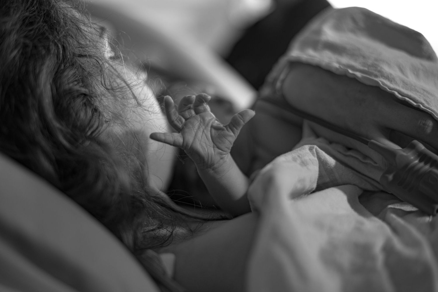 Close-up side view of patient resting in hospital bed holding newborn. Birth Photographer Ontario