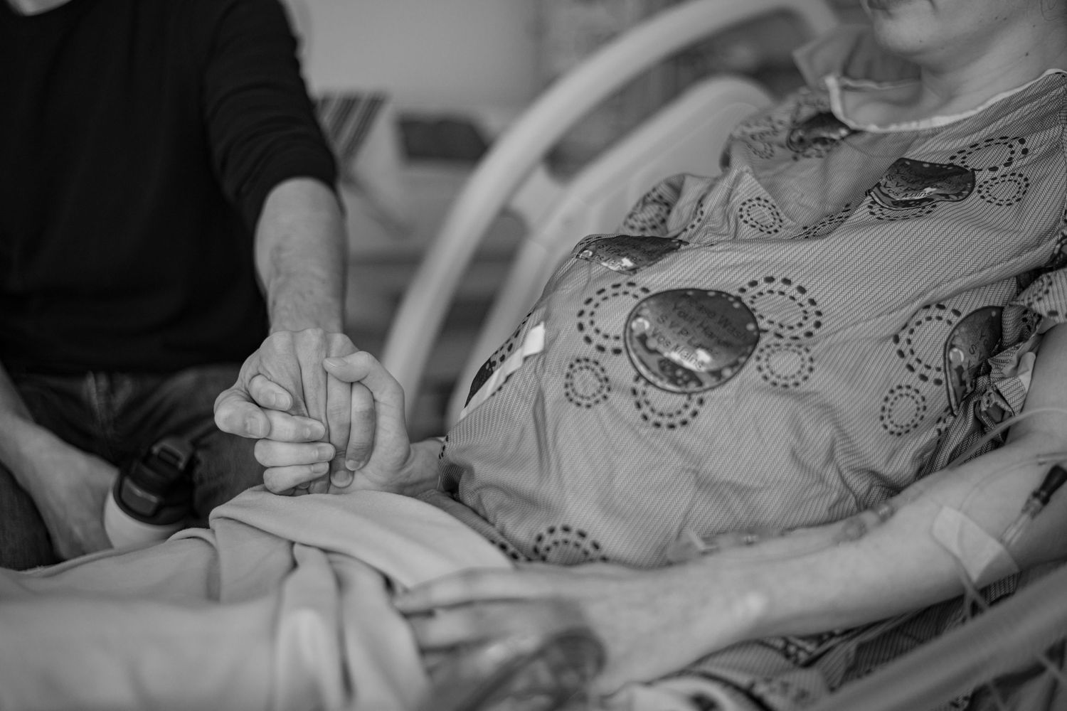 Hospital patient resting with medical equipment and patterned gown visible. Birth Photographer Ontario