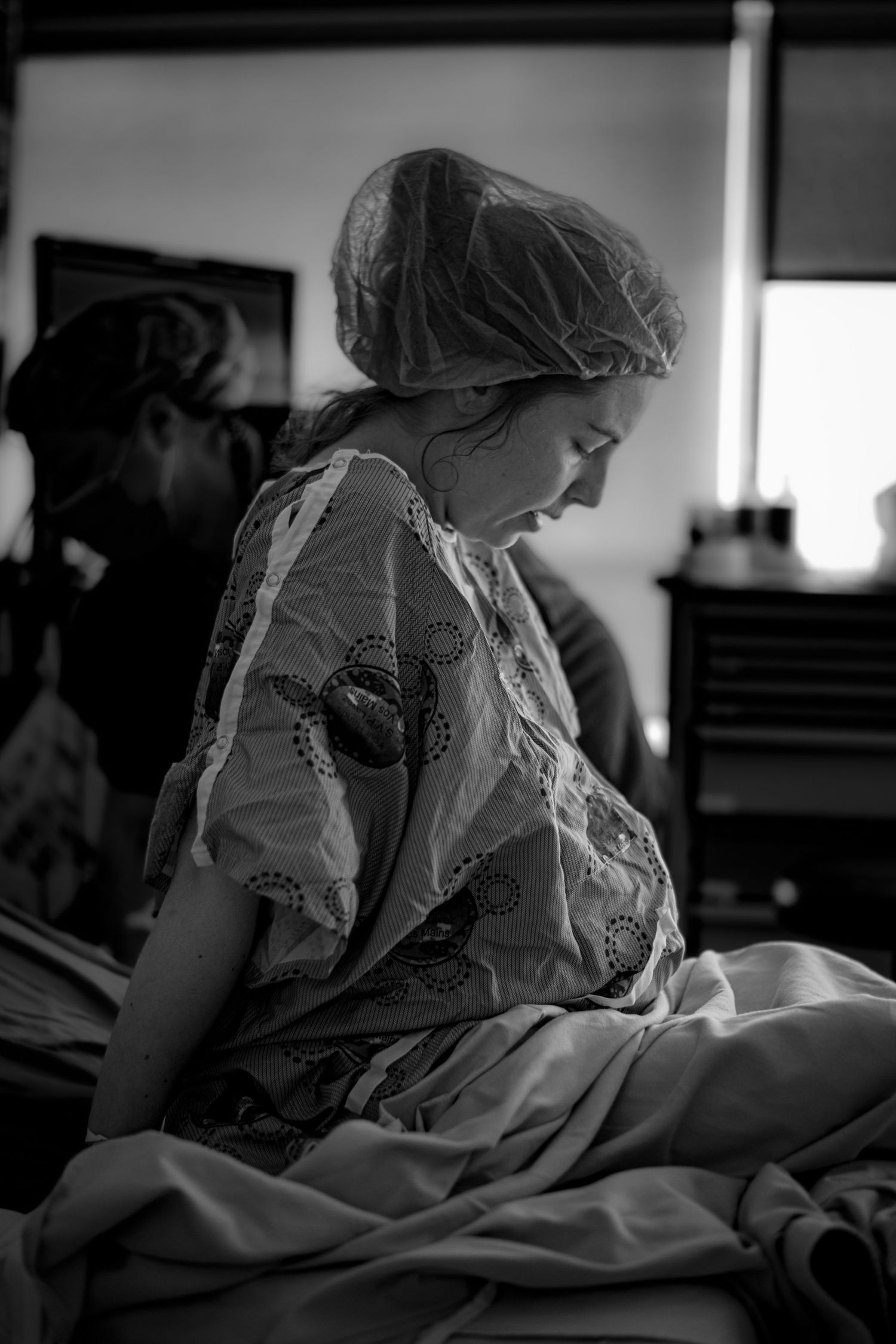 Birthing patient rests quietly on a bed in black and white. Birth Photographer Ontario
