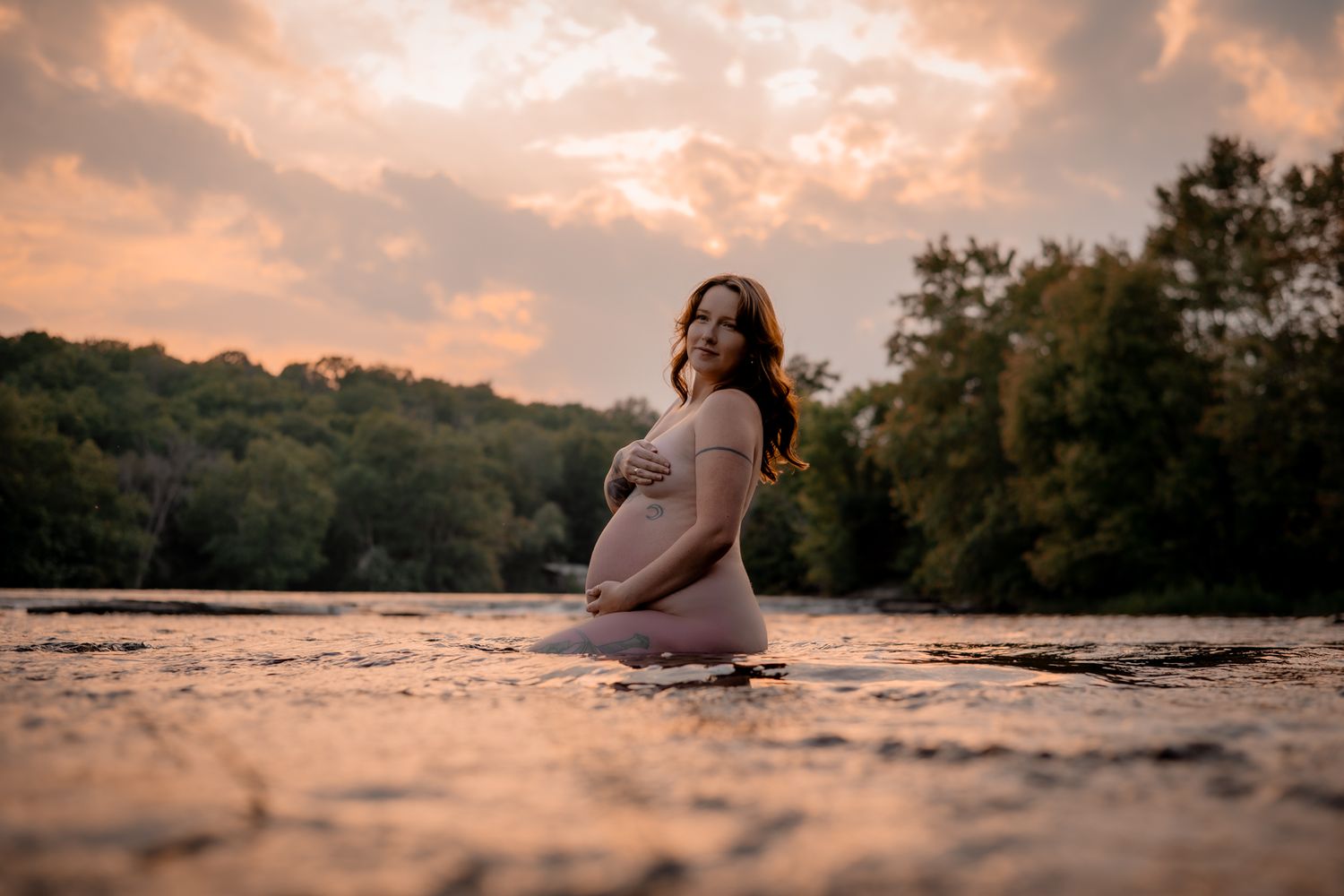 Sunset maternity photoshoot on a beach with warm golden light reflecting off the water. Maternity photographer Ontario