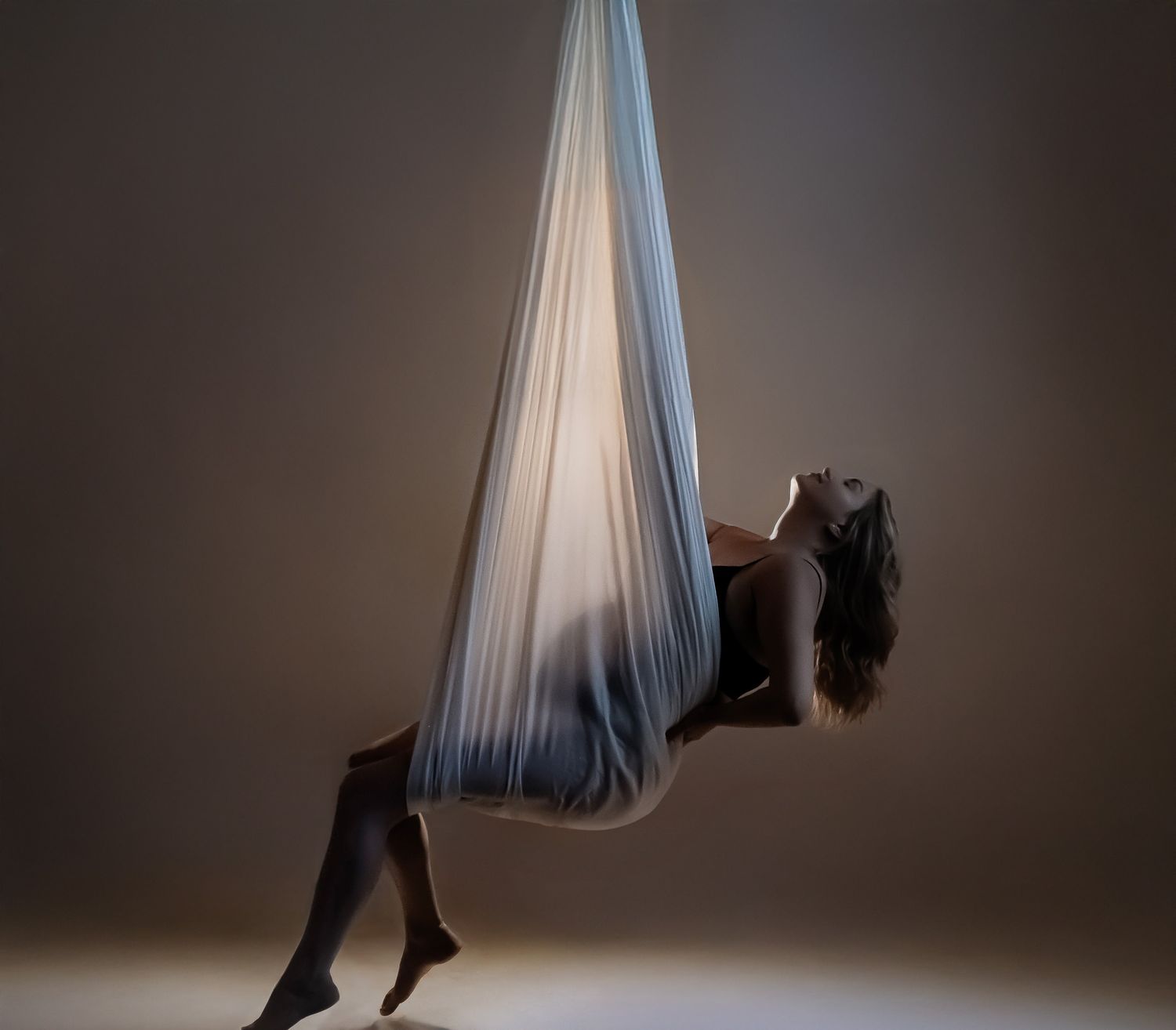 A sequence of artistic photographs showing flowing fabric in motion against a dark background with dramatic lighting.