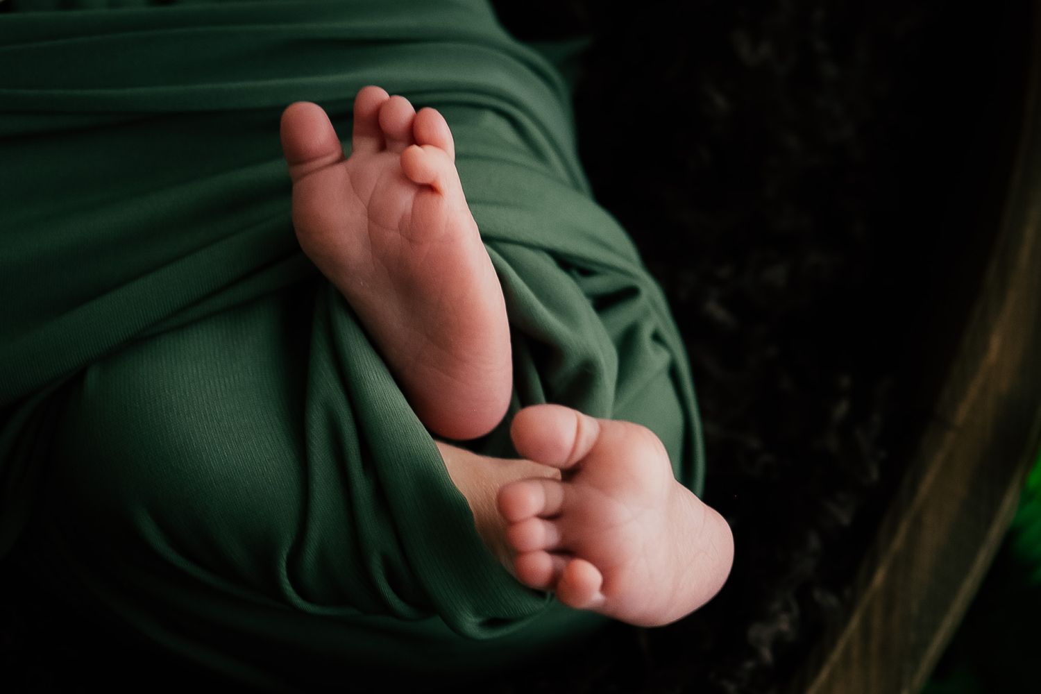 Close up of tiny newborn baby feet against dark background.