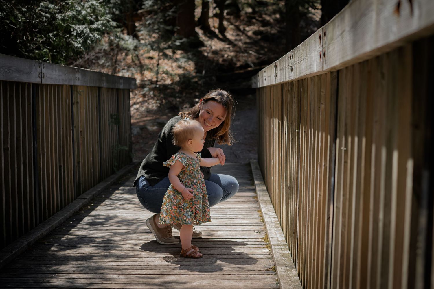 Couple sharing a romantic moment on a wooden bridge walkway during a sunny afternoon.