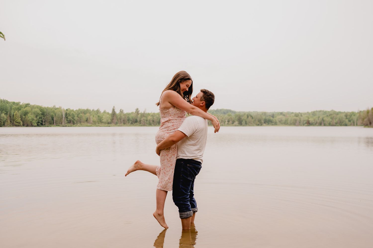 Romantic couple embraces and spins joyfully on a sandy beach during golden hour.