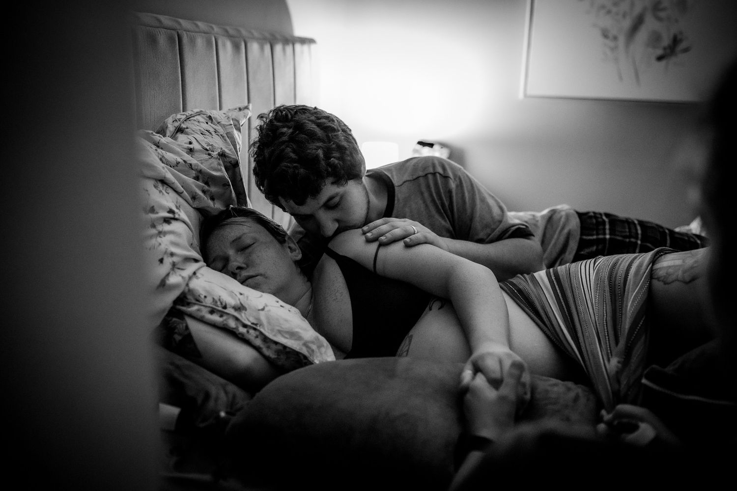 A tender black and white photograph showing two people resting peacefully together on a couch.