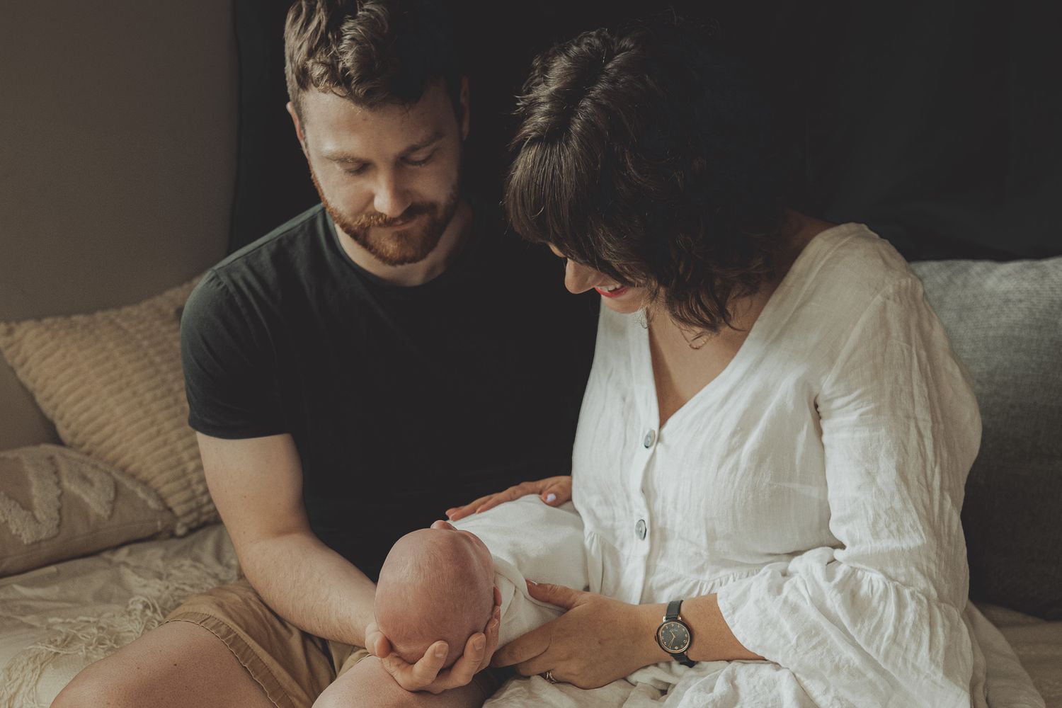 Lifestyle family photography session captured in natural light on white bedding.