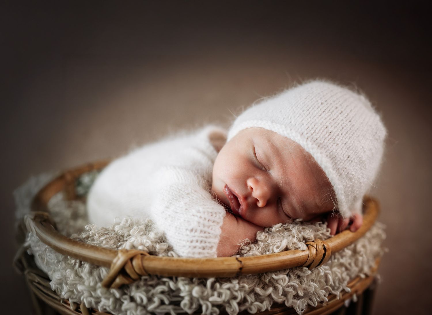 A progression of six images showing a newborn baby sleeping in a rustic wooden bowl filled with soft white fabric.
