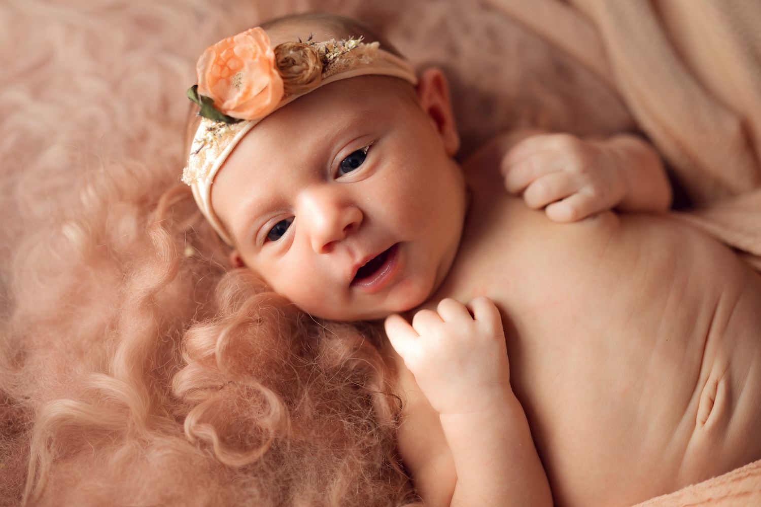 A newborn baby lies on soft pink fabric while making various sweet expressions in a series of connected photos.