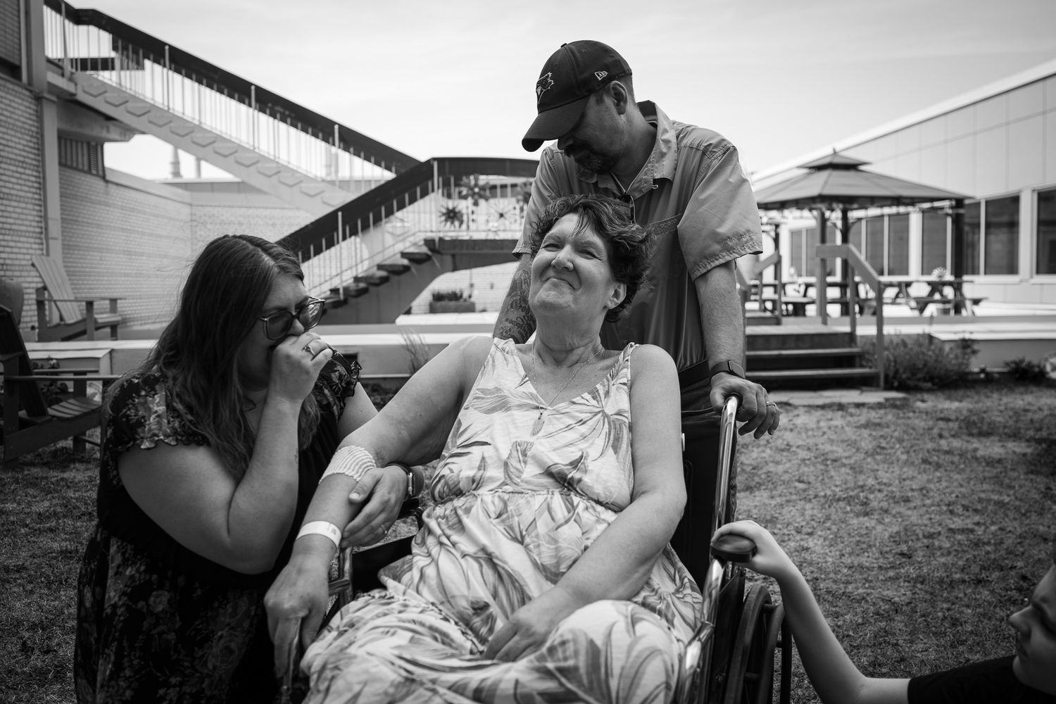 Wide shots showing emotional caregiving scenes outside medical facility with natural backdrop.