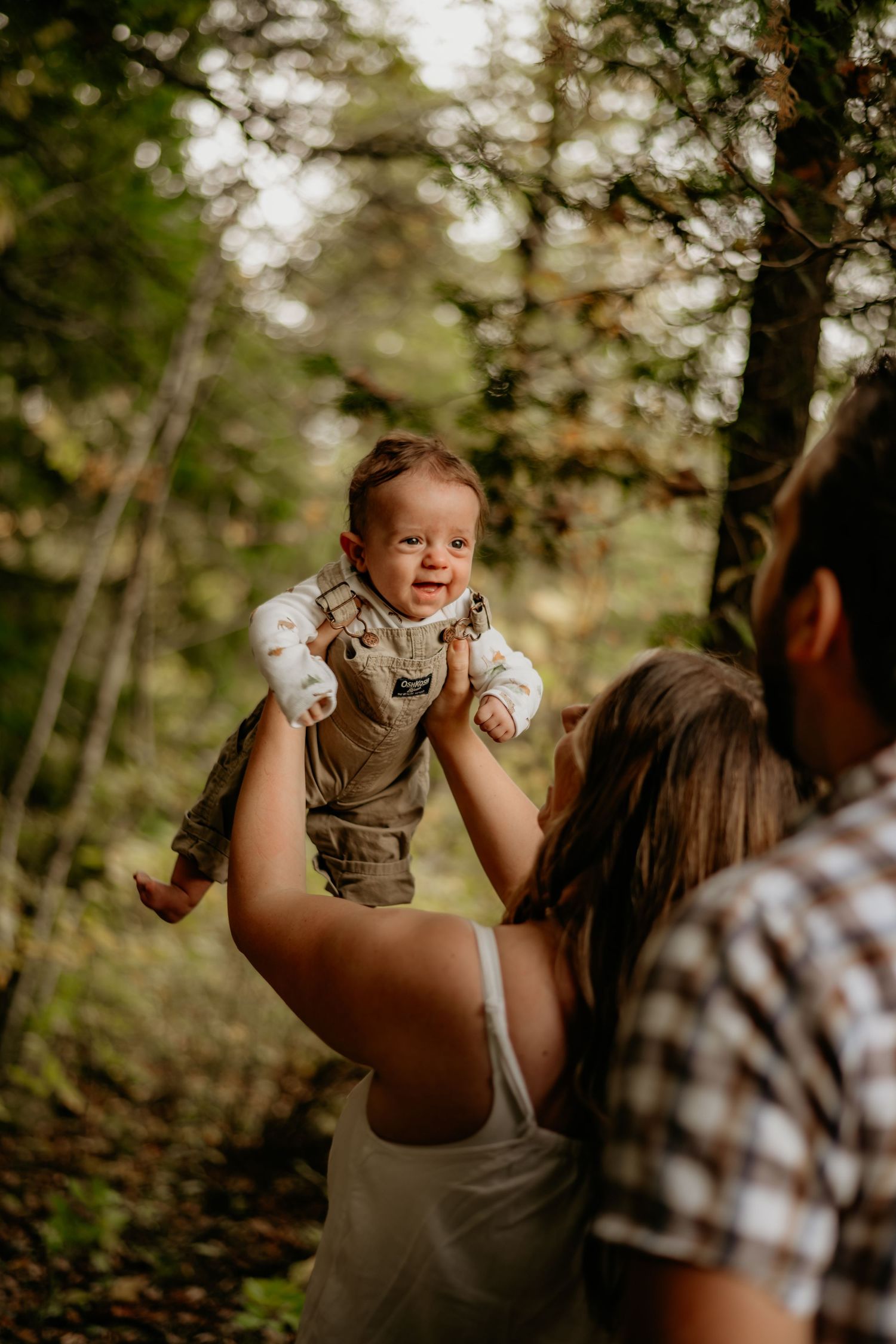 A joyful outdoor family photo session in a sunlit forest clearing.
