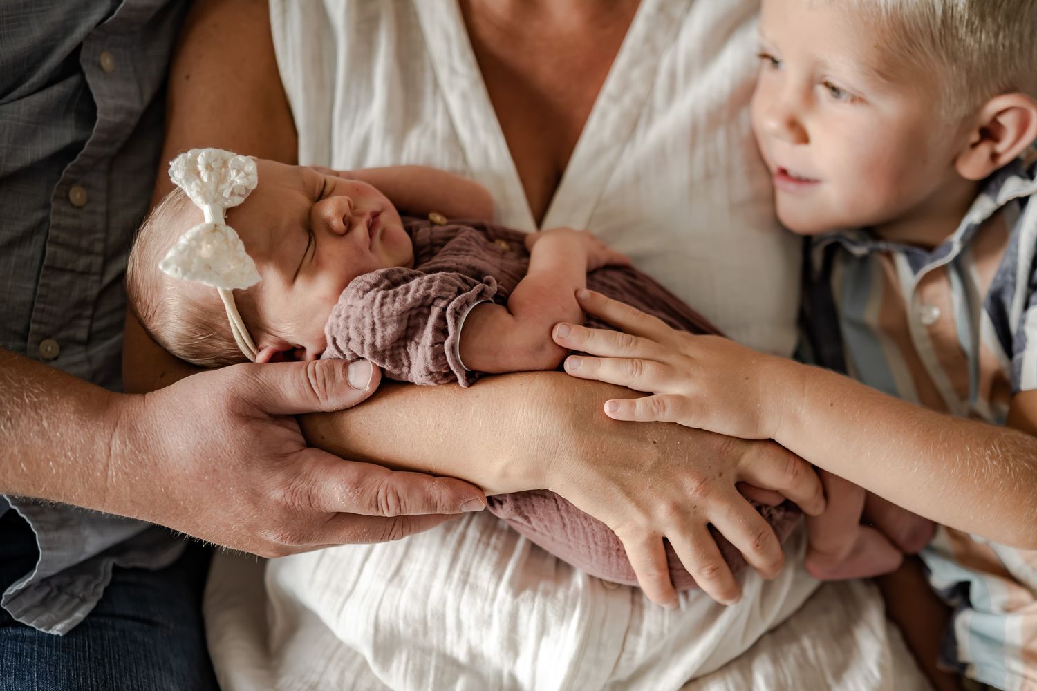 Gentle hands cradle and embrace a small infant in intimate close-up shots.