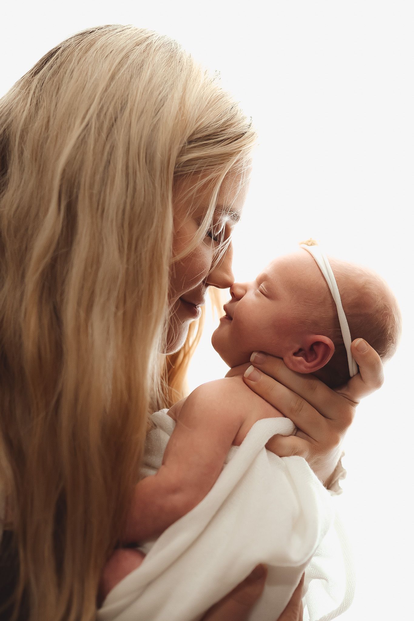 Tender moments captured between mother and infant against bright white background.