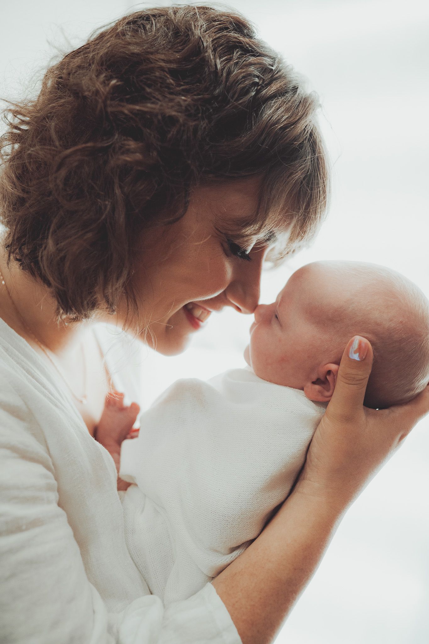 Intimate lifestyle photography session with soft white clothing and natural window light.