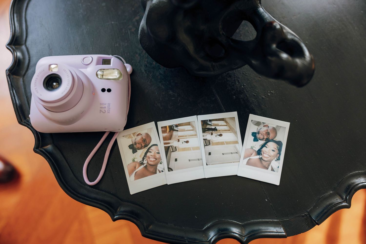Purple Fujifilm Instax Mini camera with instant photos on a black decorative table.