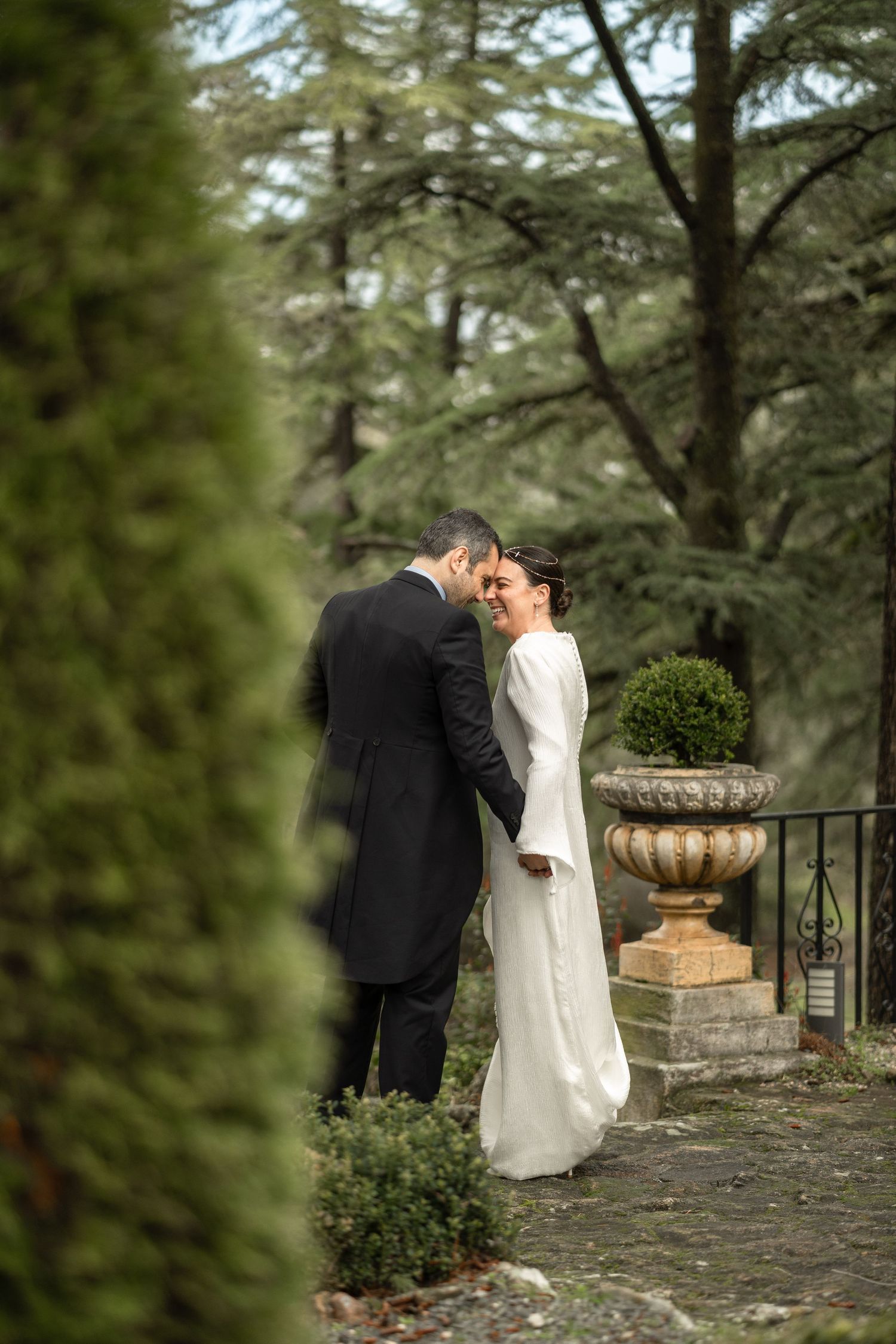 A romantic moment between newlyweds in an elegant garden setting with stone decorative elements.