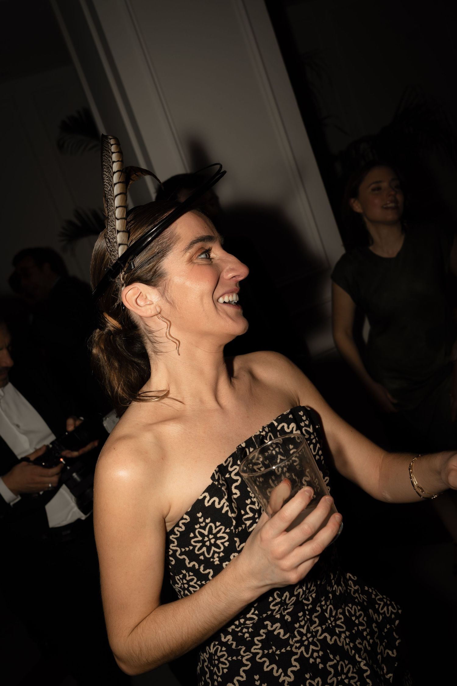 Person in a sequined dress laughs joyfully at a dark indoor event.