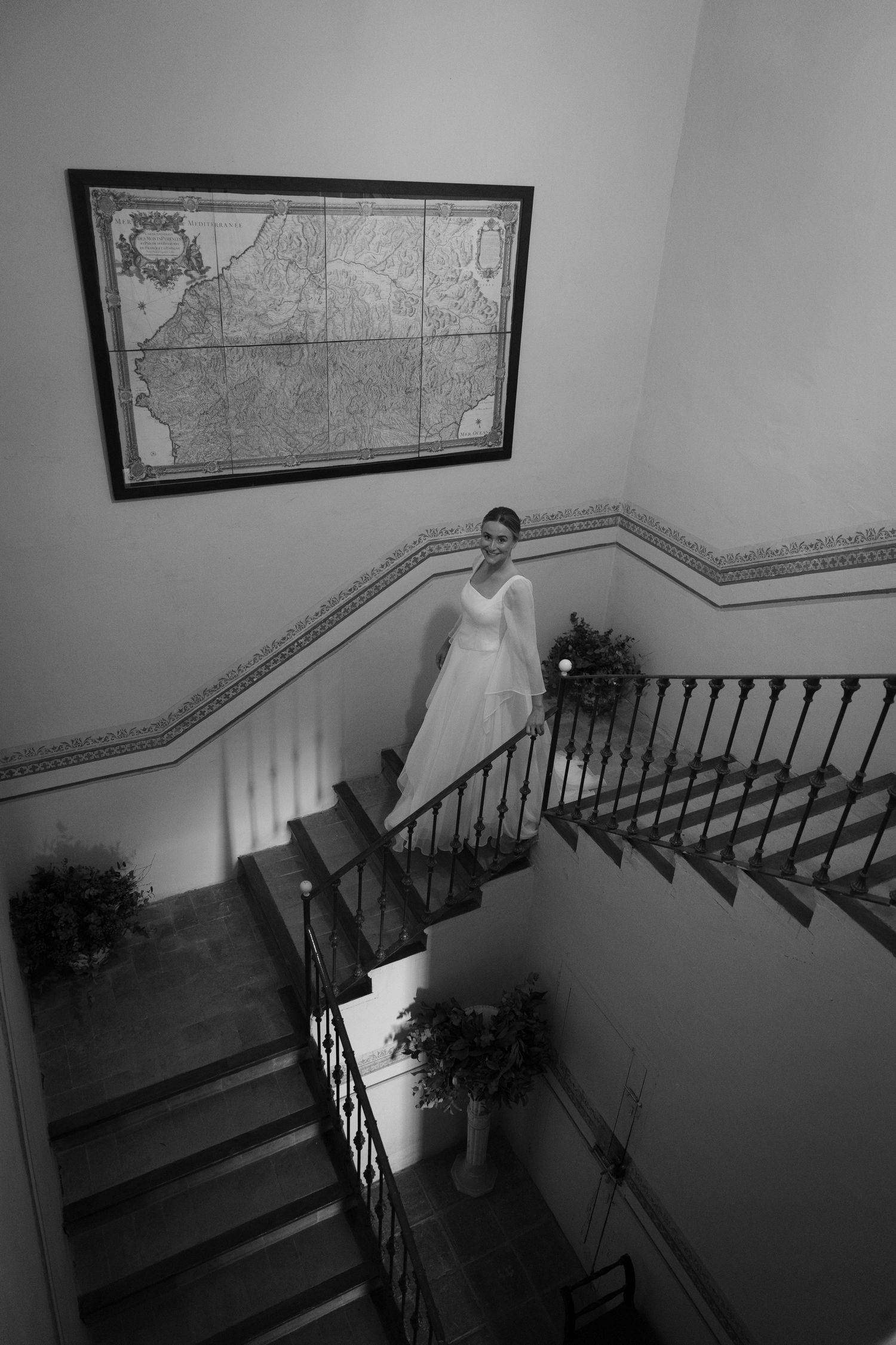 High angle view of bride on elegant staircase with vintage map on wall.