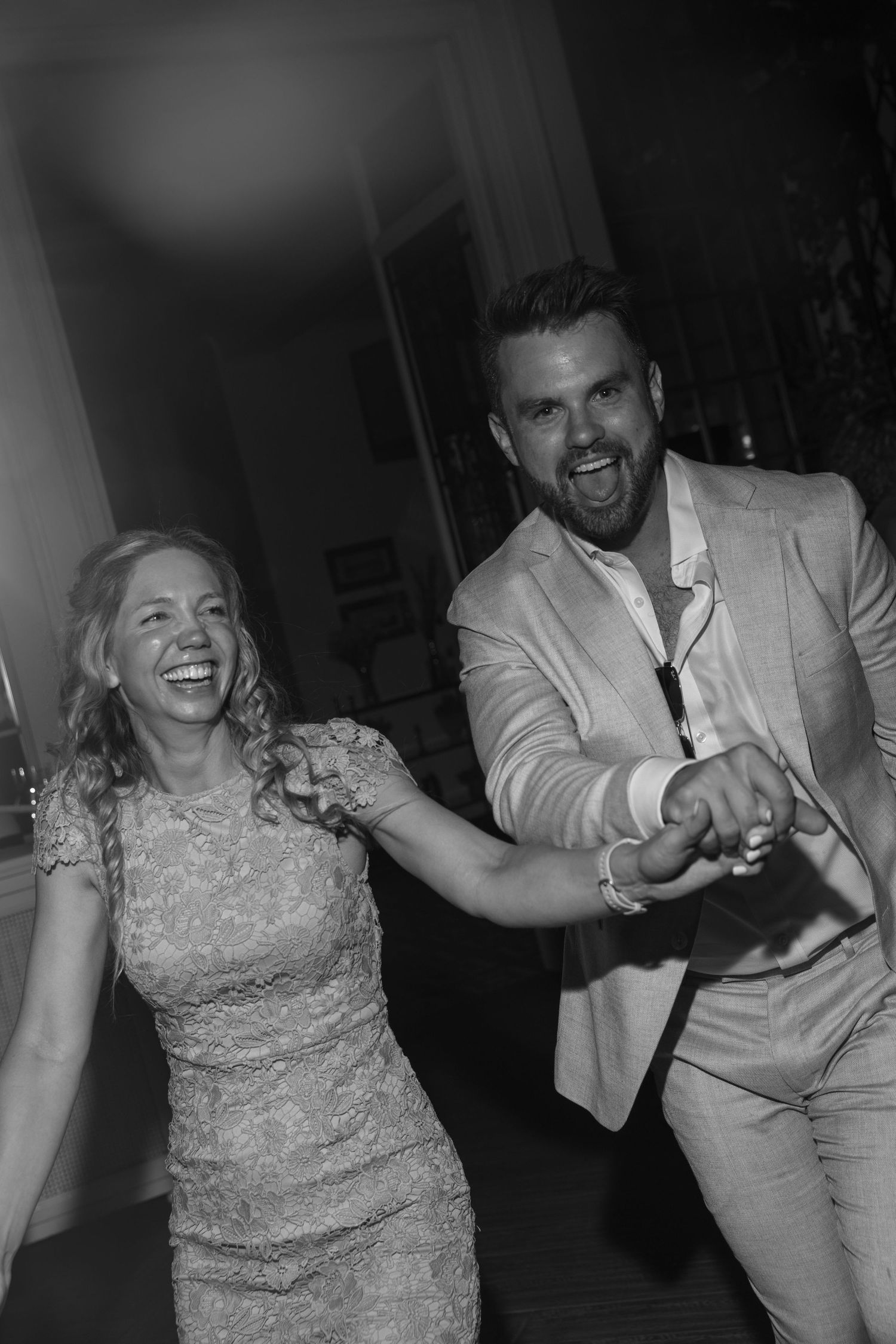 Couple dancing and laughing together at a party in formal attire.