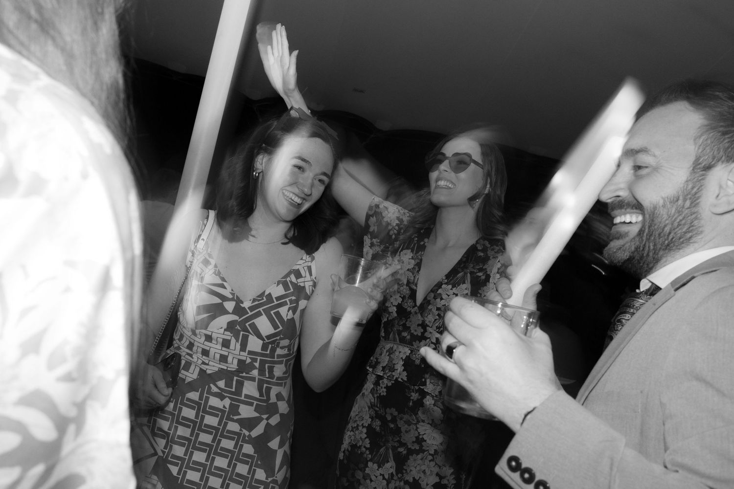 Candid black and white photo of party guests laughing and dancing together.