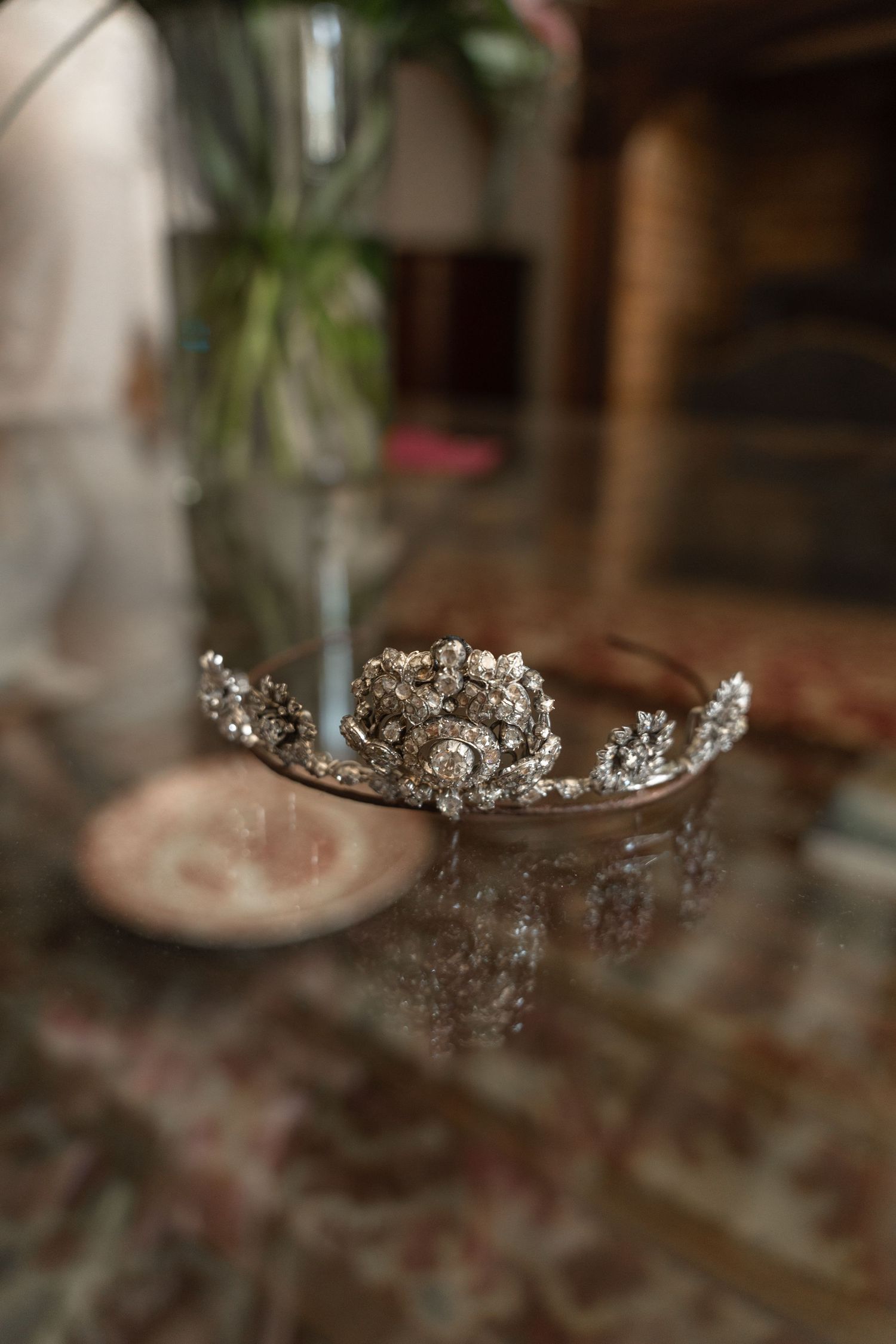 Crystal bridal tiara on wooden table with floral decorations.